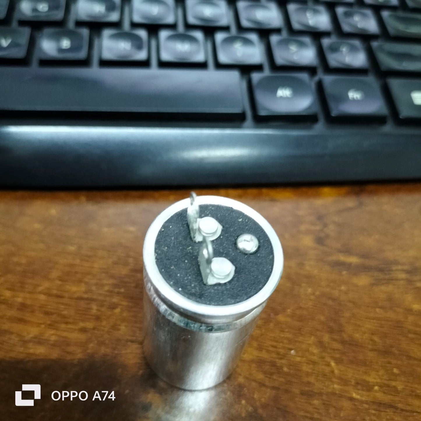 SH brand 1.25MFD 250V AC capacitor with metal casing and two terminals on a wooden surface