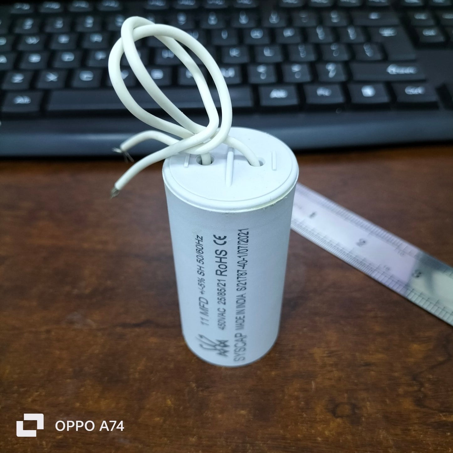 Syscap 11MFD 450 VAC Running Capacitor cylindrical electrical component with white wires on wooden surface