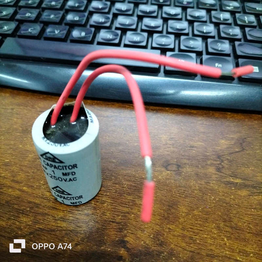 DRE 1MFD 250V AC motor running capacitor with red wires on a wooden surface