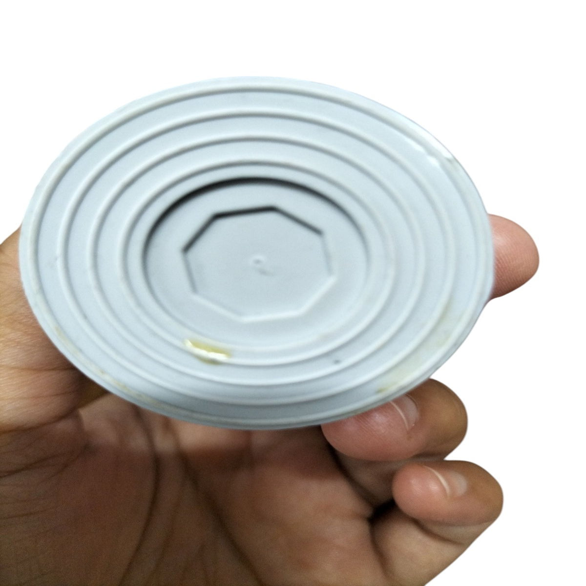 Hand holding a 450V AC Running Capacitor showing the underside with circular grooves