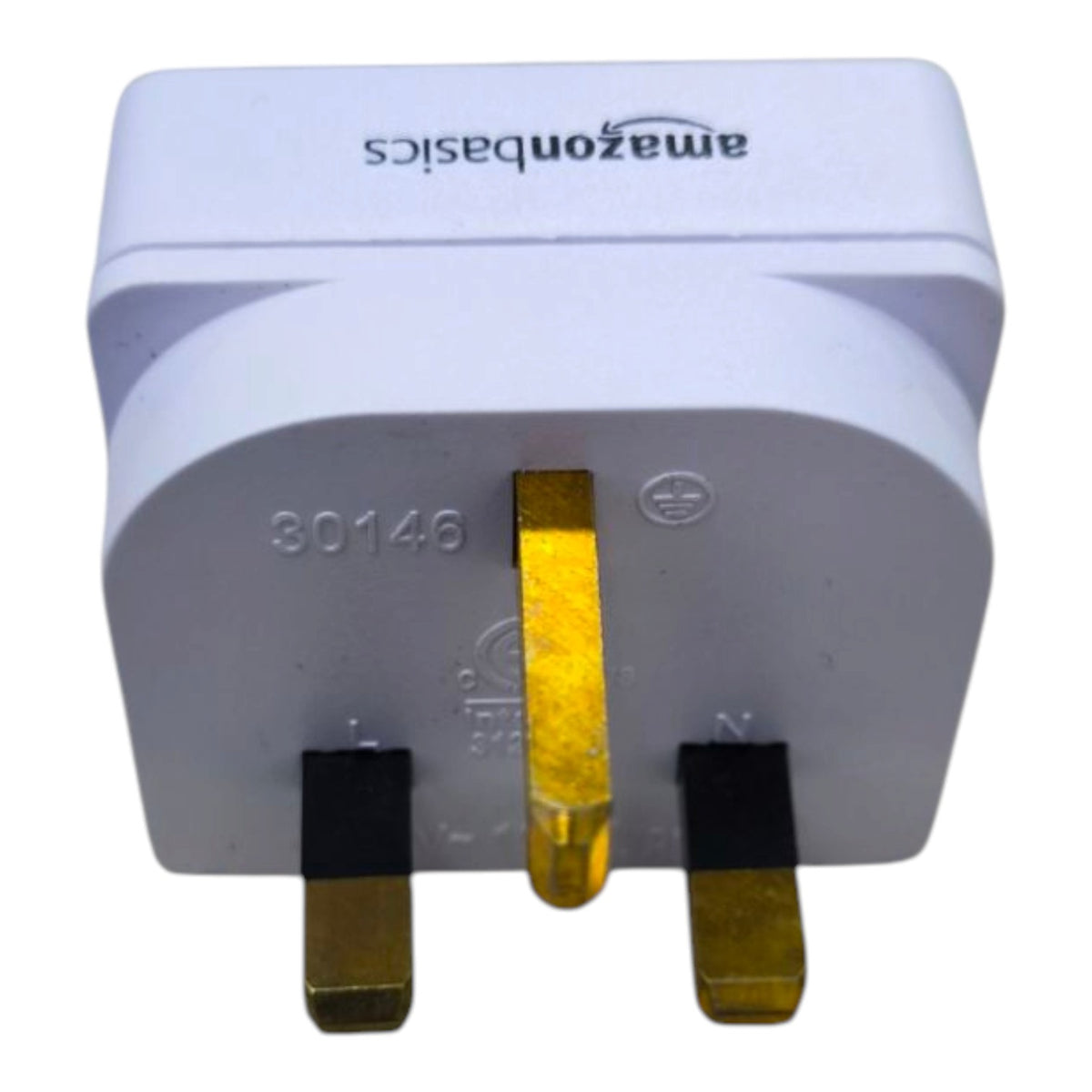 White Amazon Basics UK three-pin wall plug adapter with gold-plated metal prongs and black terminal markings, shown on a plain white background.