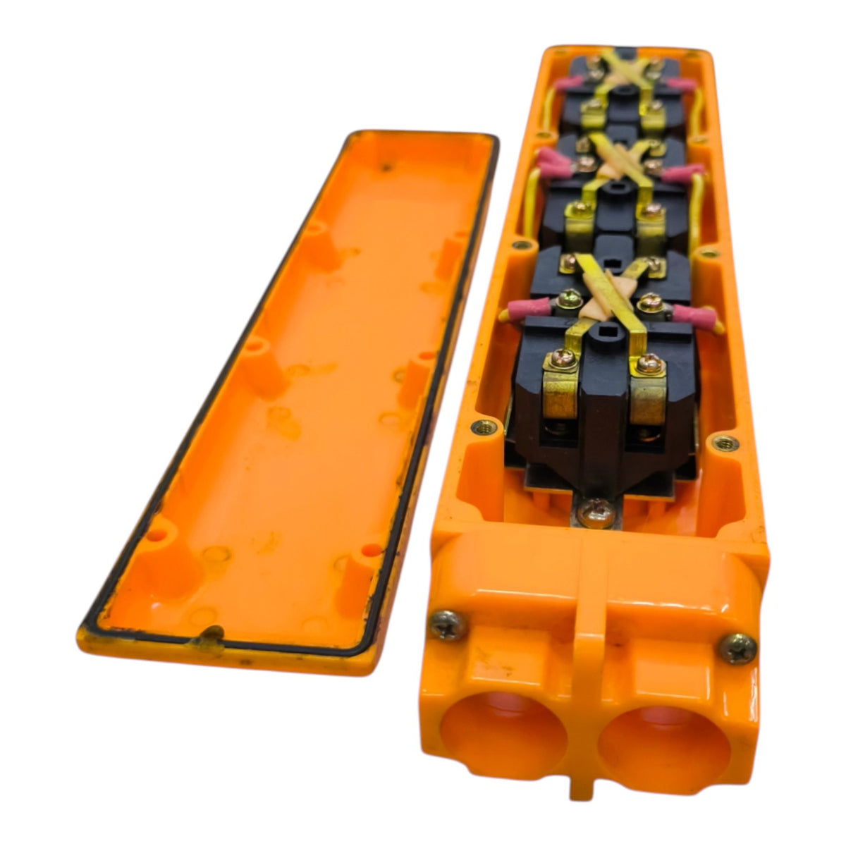 An orange electrical terminal block or connector housing shown open, with the inner cover removed and placed beside it. The interior contains black terminal components with yellow and pink wire leads and metal screw terminals, photographed on a plain white background.