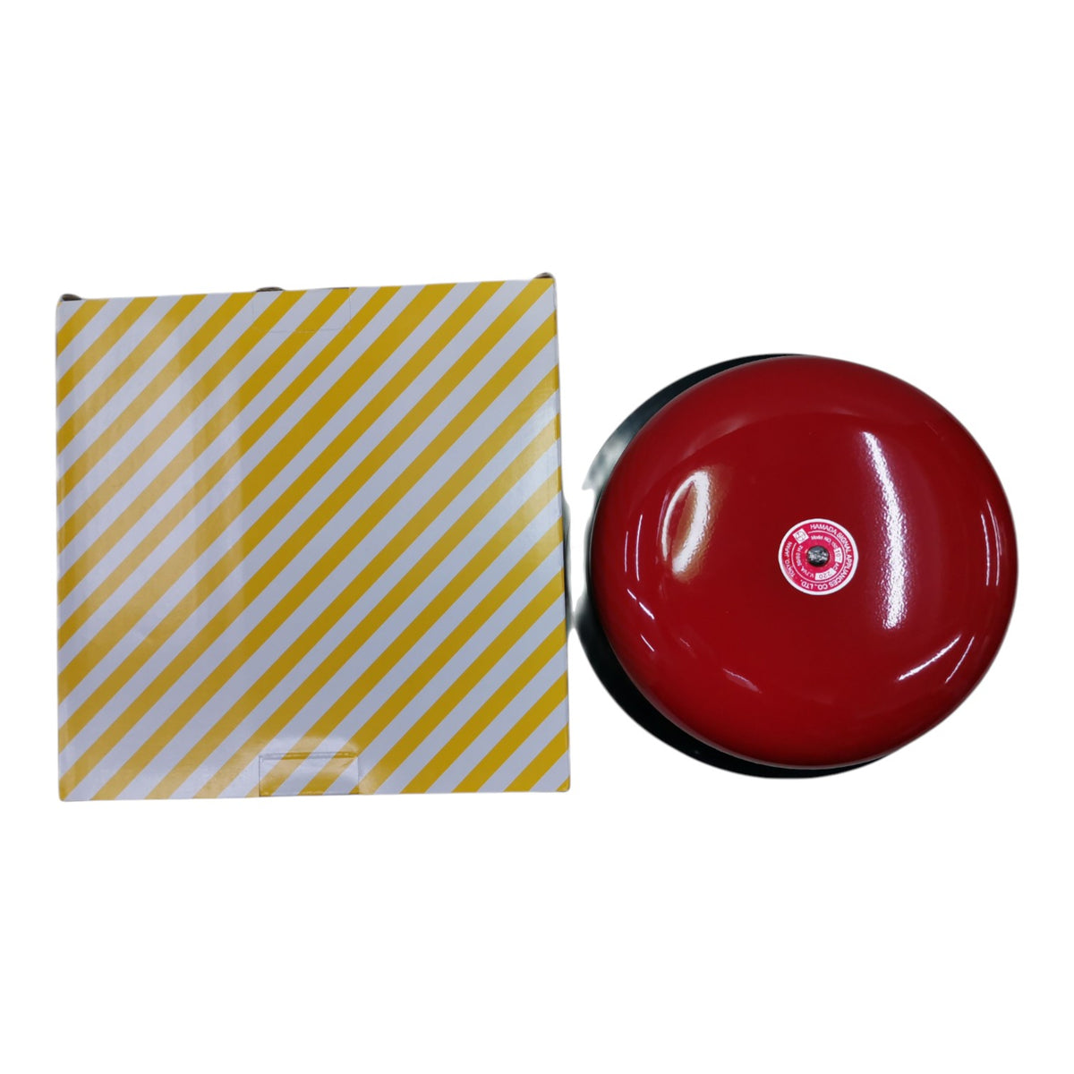 A red dome-shaped fire alarm bell shown next to its yellow and white diagonally striped packaging box on a plain white background.