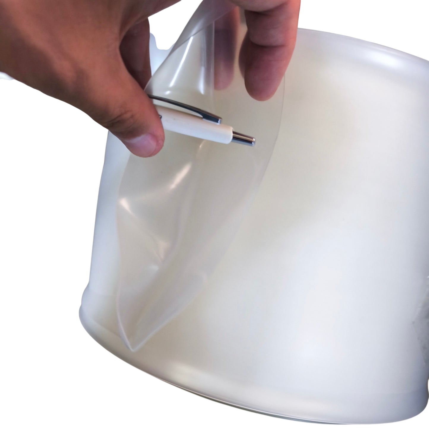 Hand holding a white and silver object over a white container on a white background