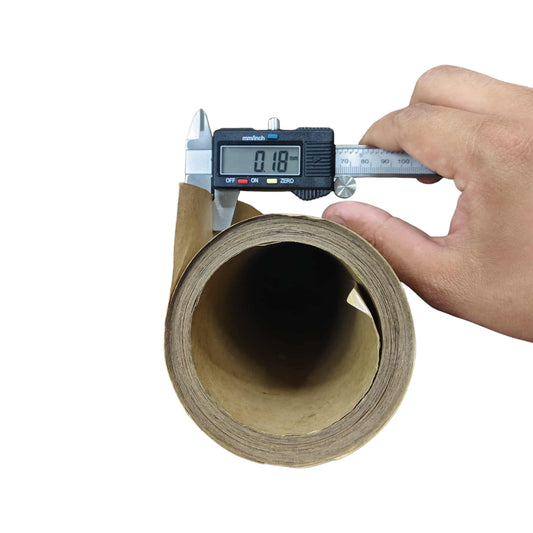 Roll of cardboard with a digital caliper measuring its thickness on a white background