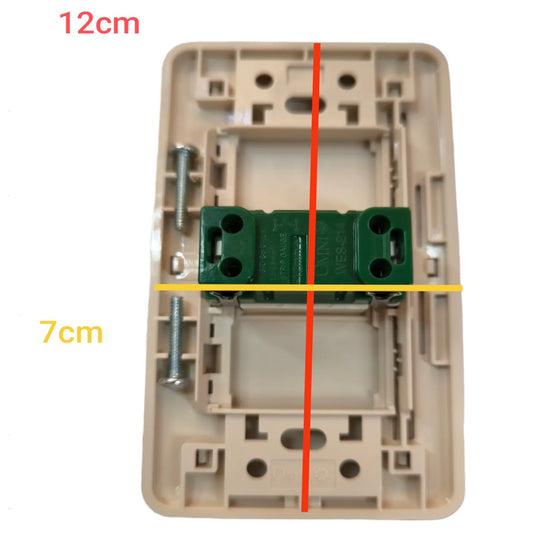 A beige plastic electrical switch socket backplate with a green terminal block and mounting screw, overlaid with red and yellow measurement lines and text indicating 12cm and 7cm dimensions.