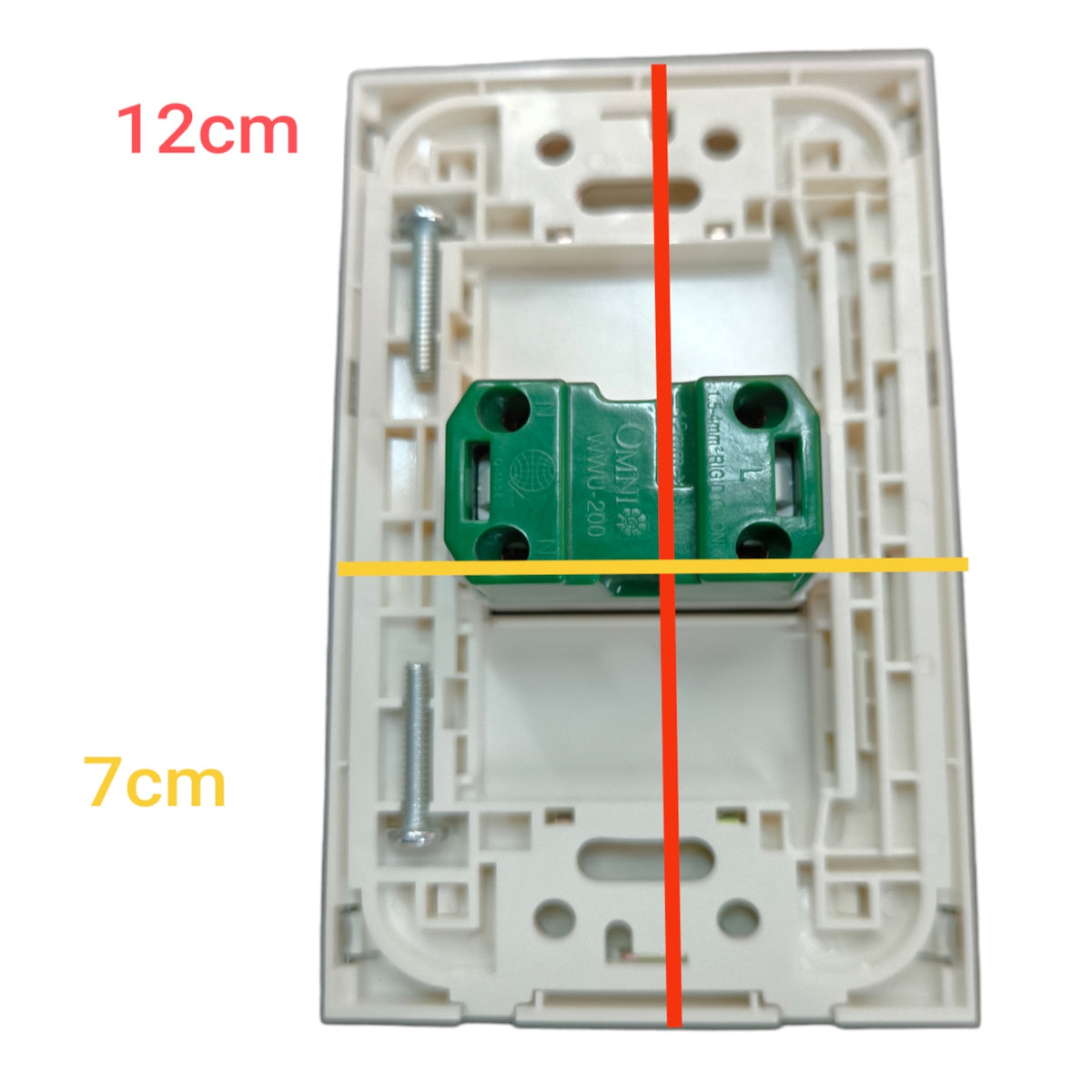A white plastic electrical switch plate with a green terminal block connector in the center, overlaid with red and yellow measurement lines and text indicating 12cm height and 7cm width.