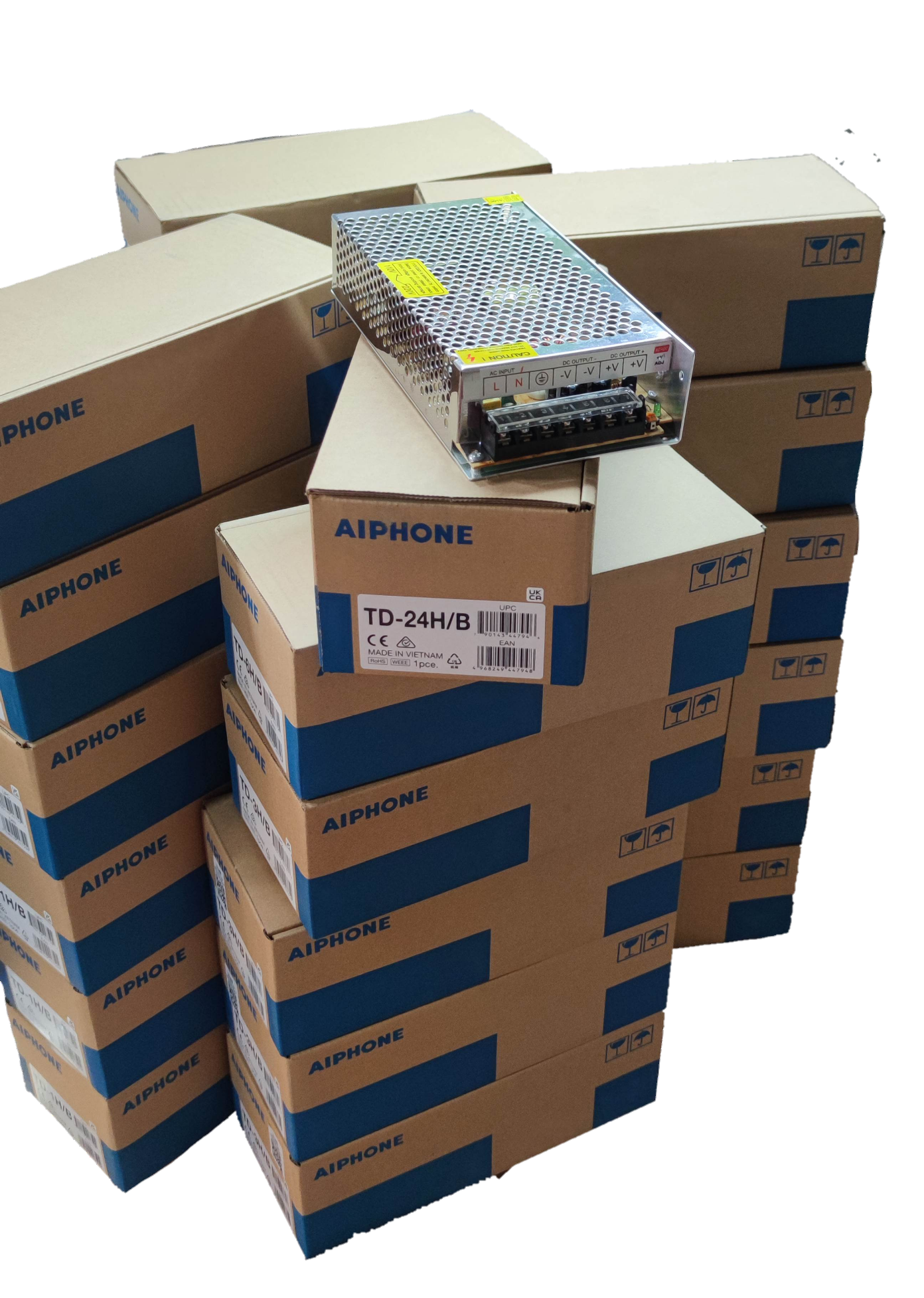 Aiphone 24 station intercom system components stacked in labeled boxes with a metal power supply unit on top