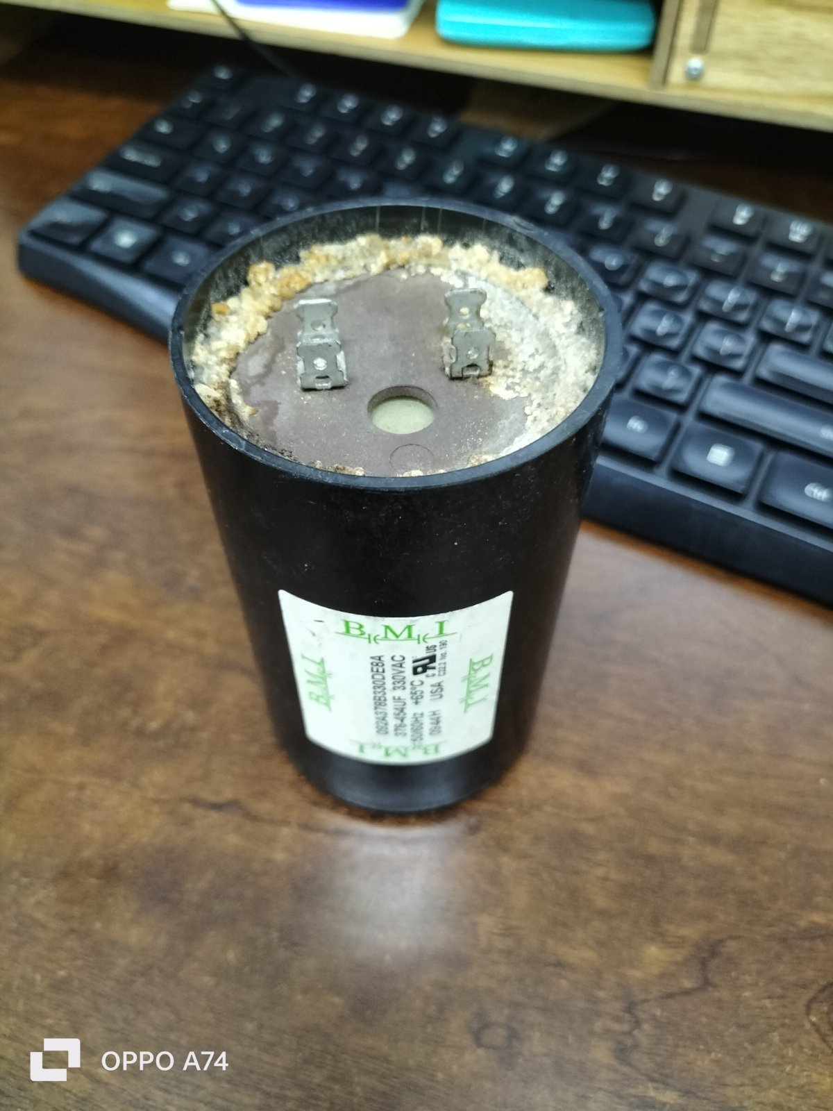 BMI 378-454UF starting capacitor black cylindrical electrical component on wooden desk