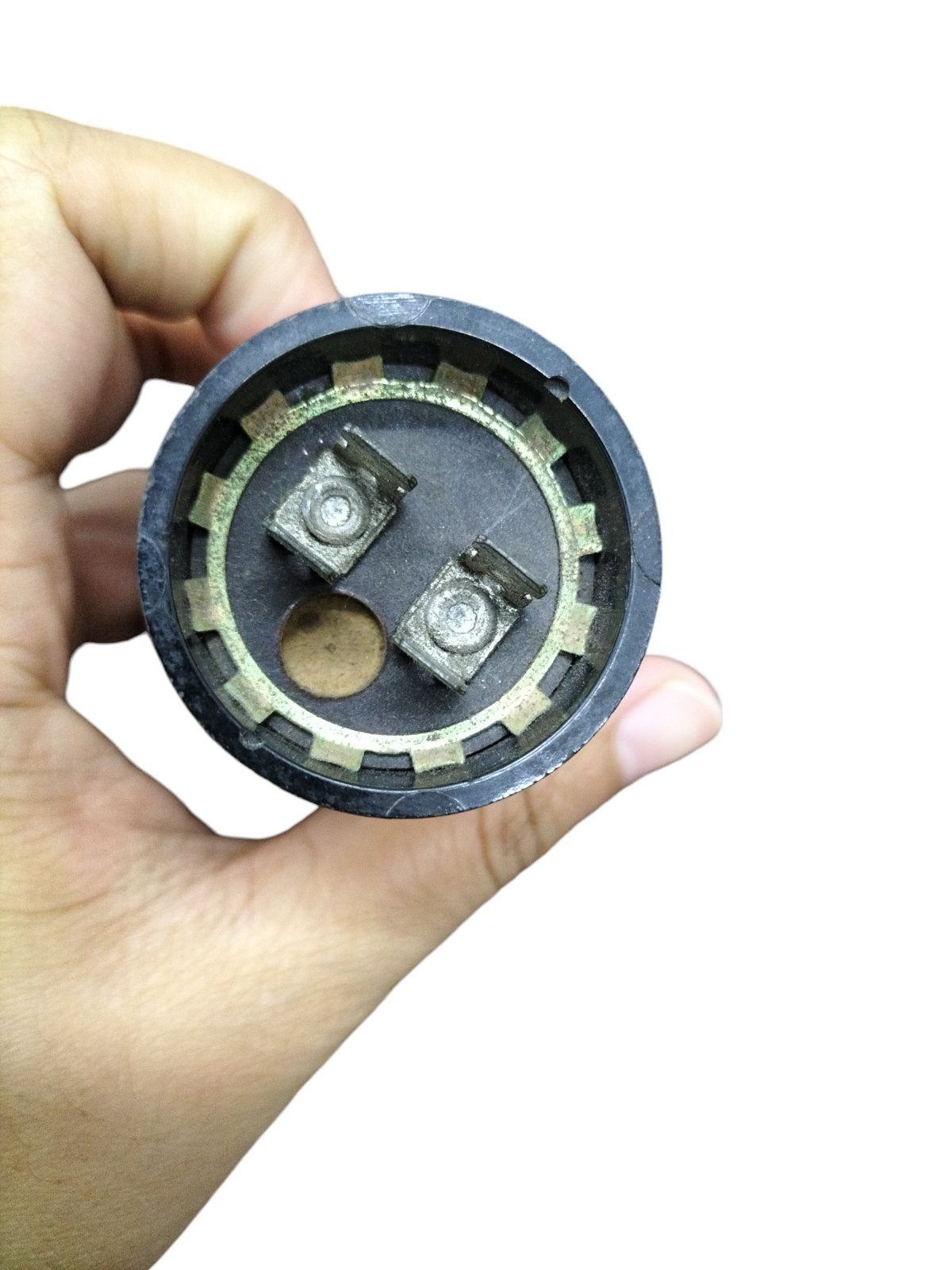 Hand holding BMI motor capacitor base with two terminals for Starting Capacitor 64-77MFD 250V replacement
