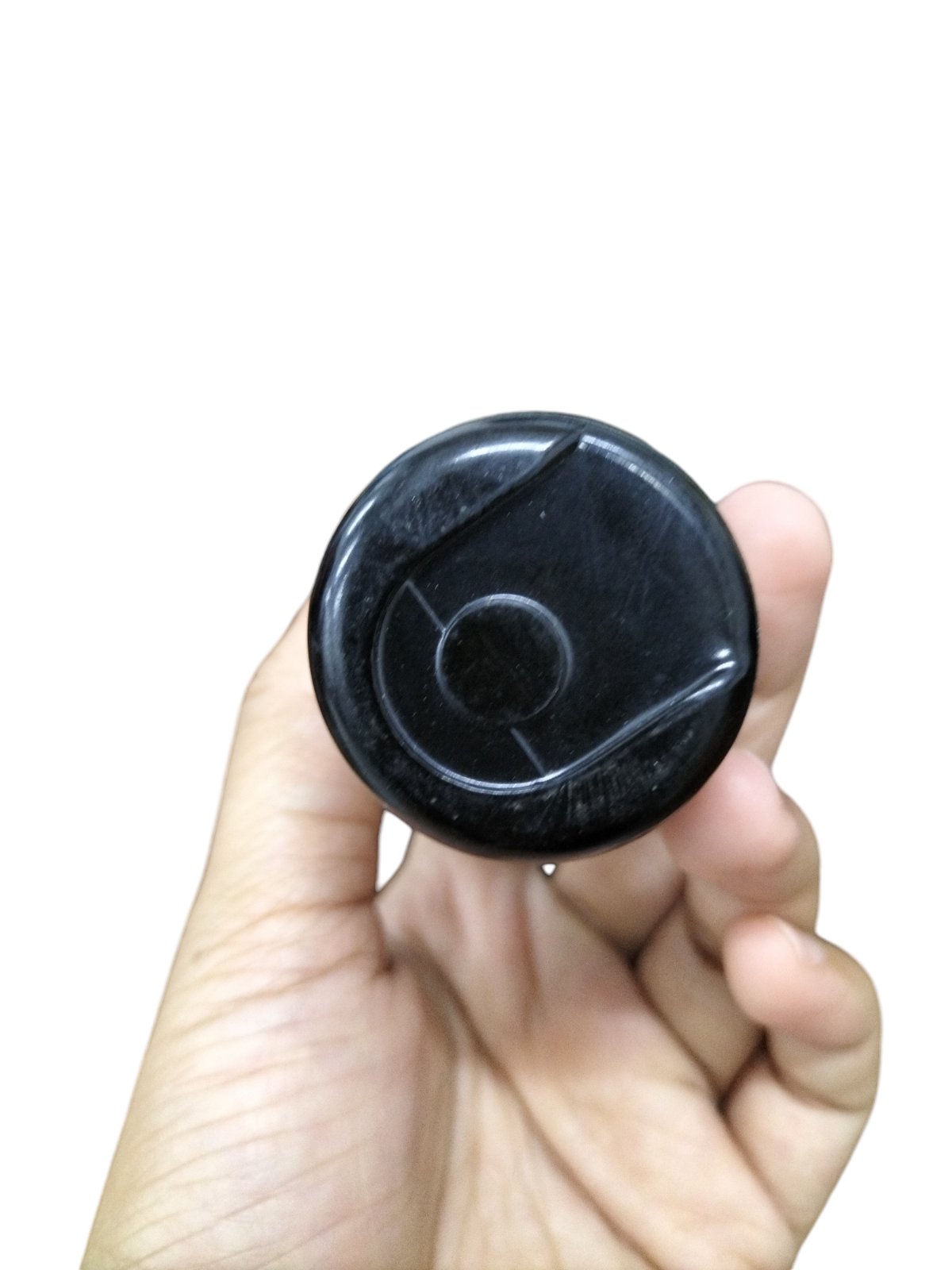 BMI Starting Capacitor 64-77MFD 250V round black plastic housing held in hand showing top view and terminals