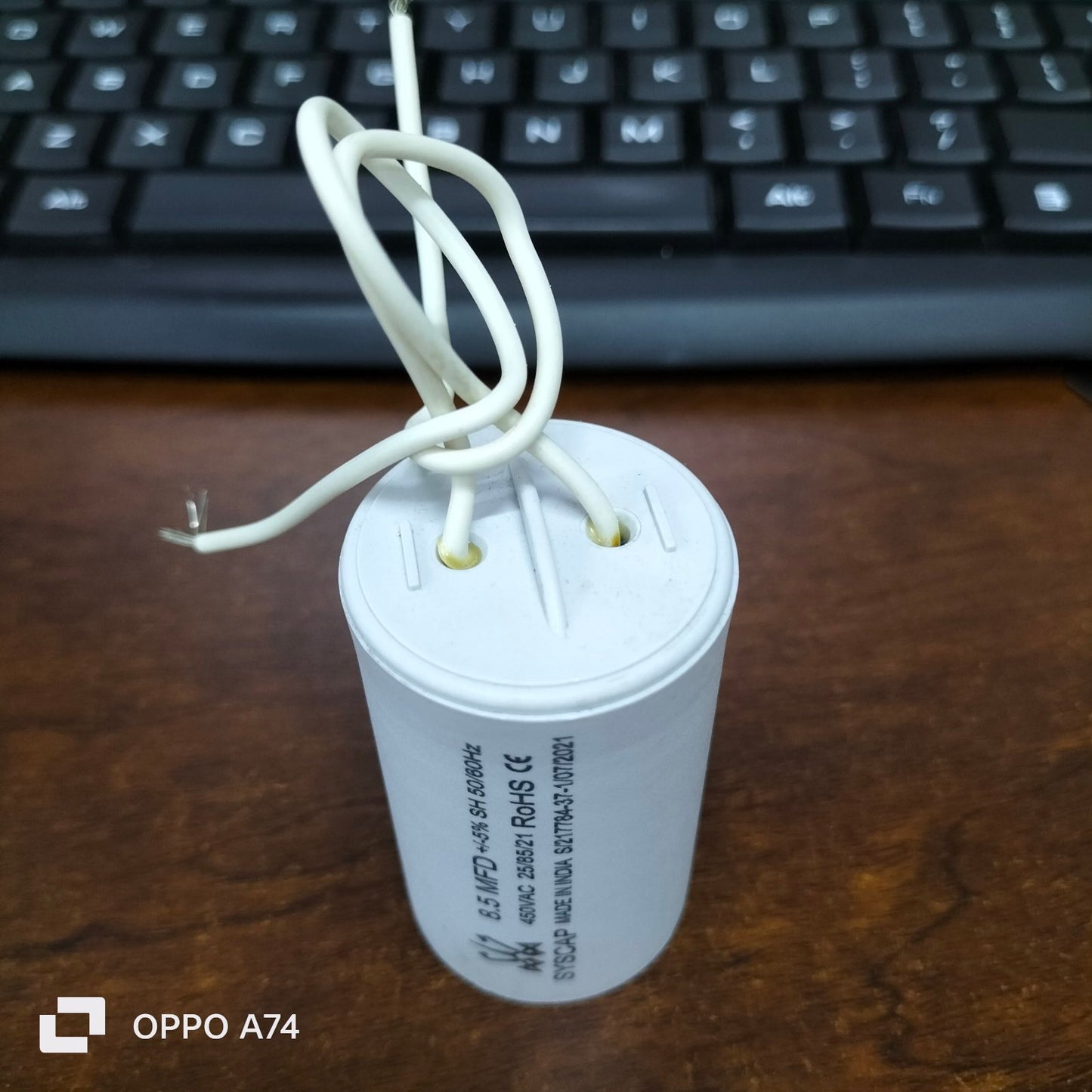 Syscap 8.5MFD 450 VAC Running Capacitor white cylindrical with attached wires on wooden surface
