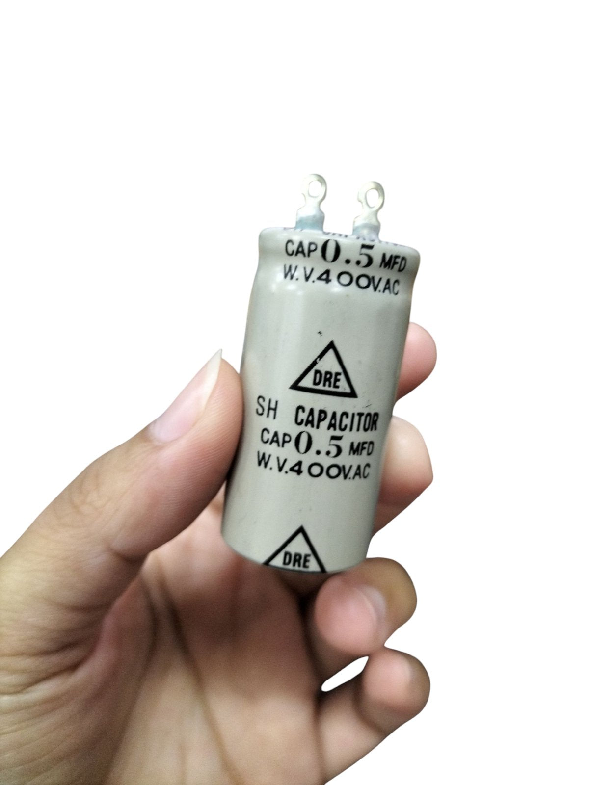 DRE 0.5MFD Motor Running Capacitor held in hand, white cylindrical electrical component