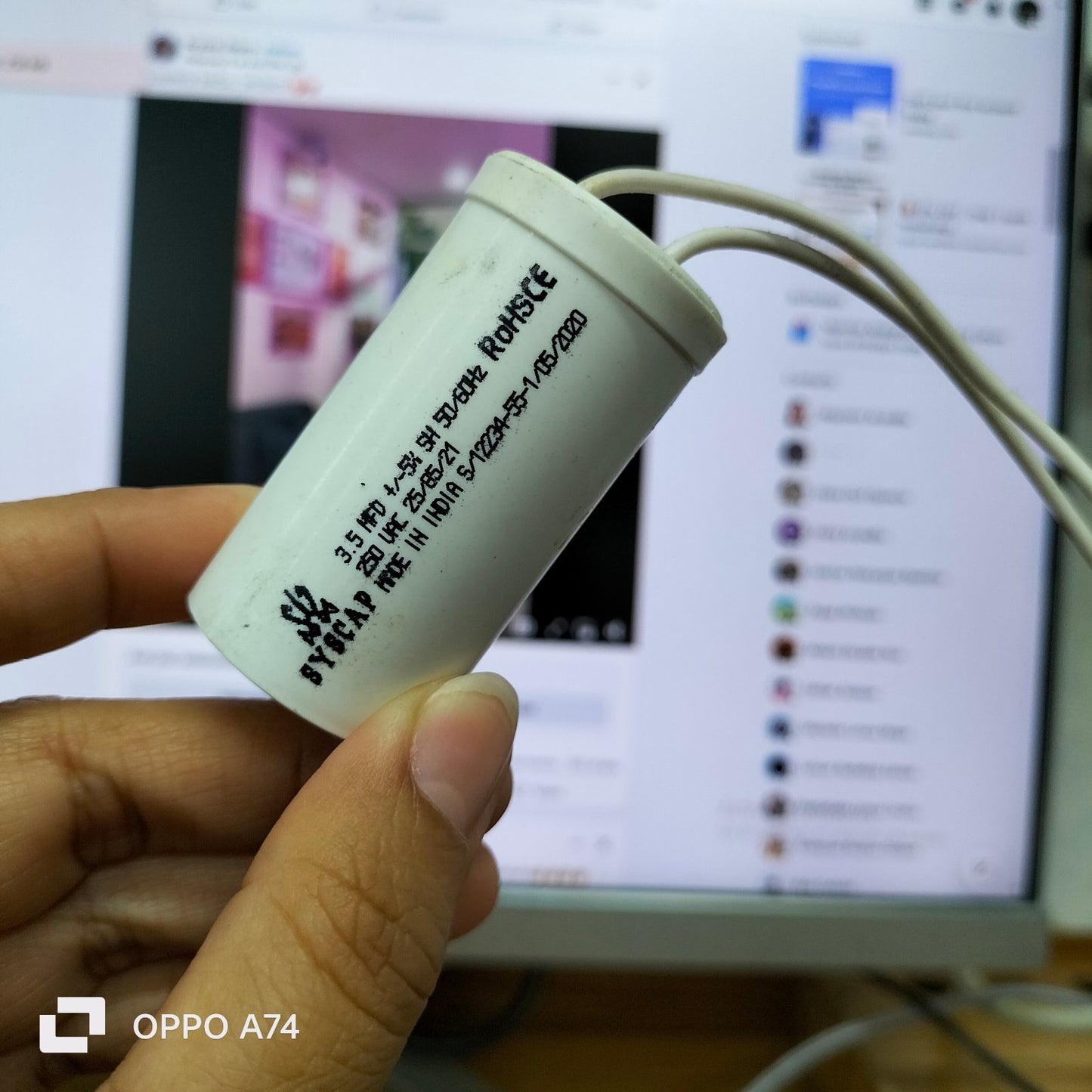 Syscap 250 VAC 3.5MFD Running Capacitor held in hand with white wires for electrical circuitry