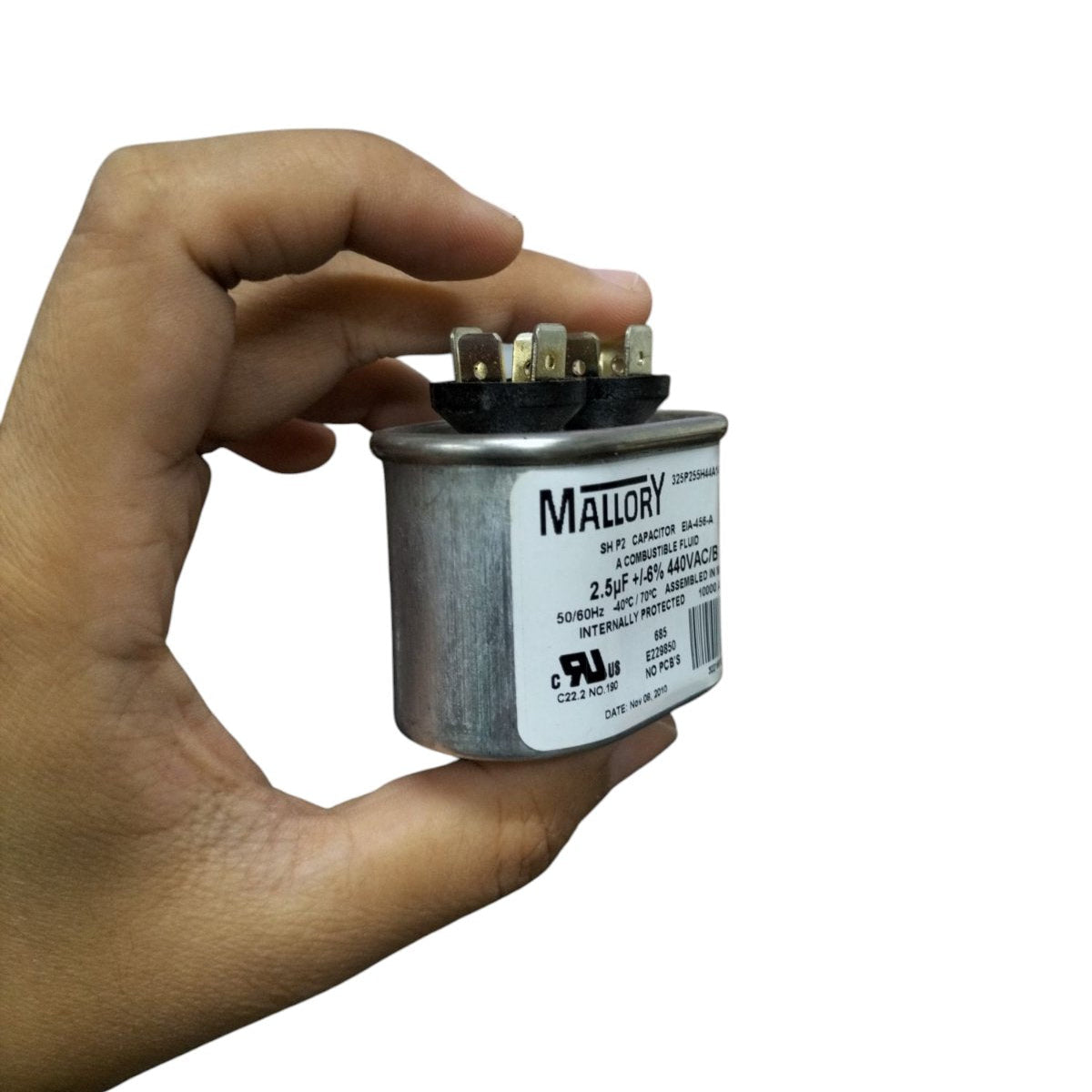 Mallory 440V running capacitor held in hand with clear label and connection terminals visible