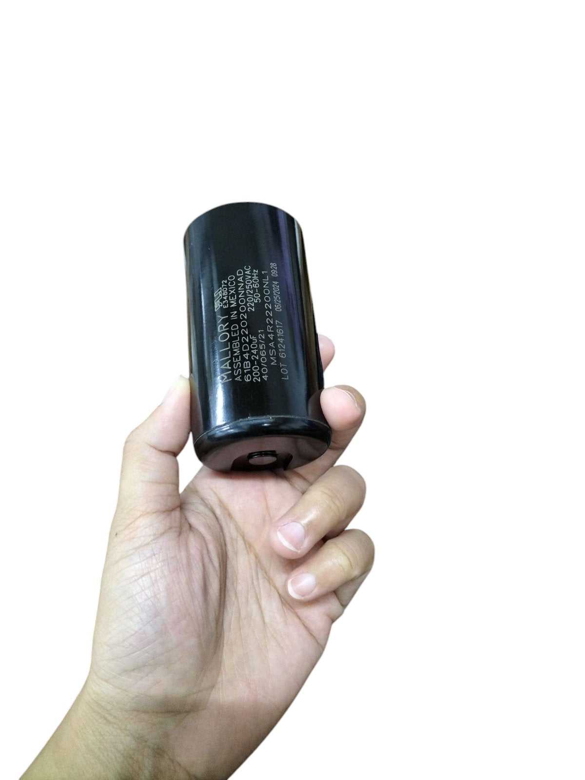 Mallory black motor capacitor held in hand for electrical circuitry and parts