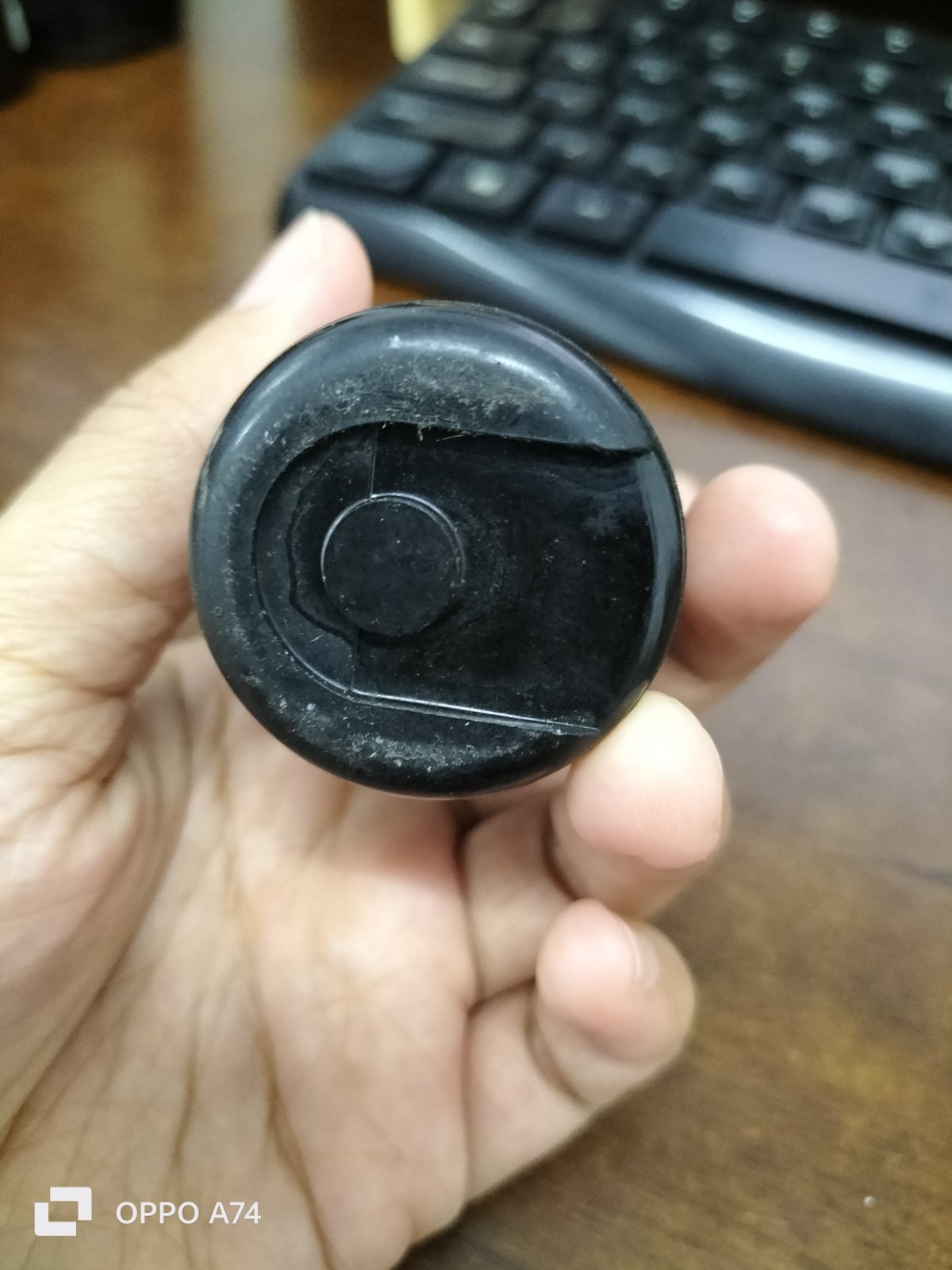Hand holding black motor starting capacitor 280-366 MFD electrical component with keyboard background
