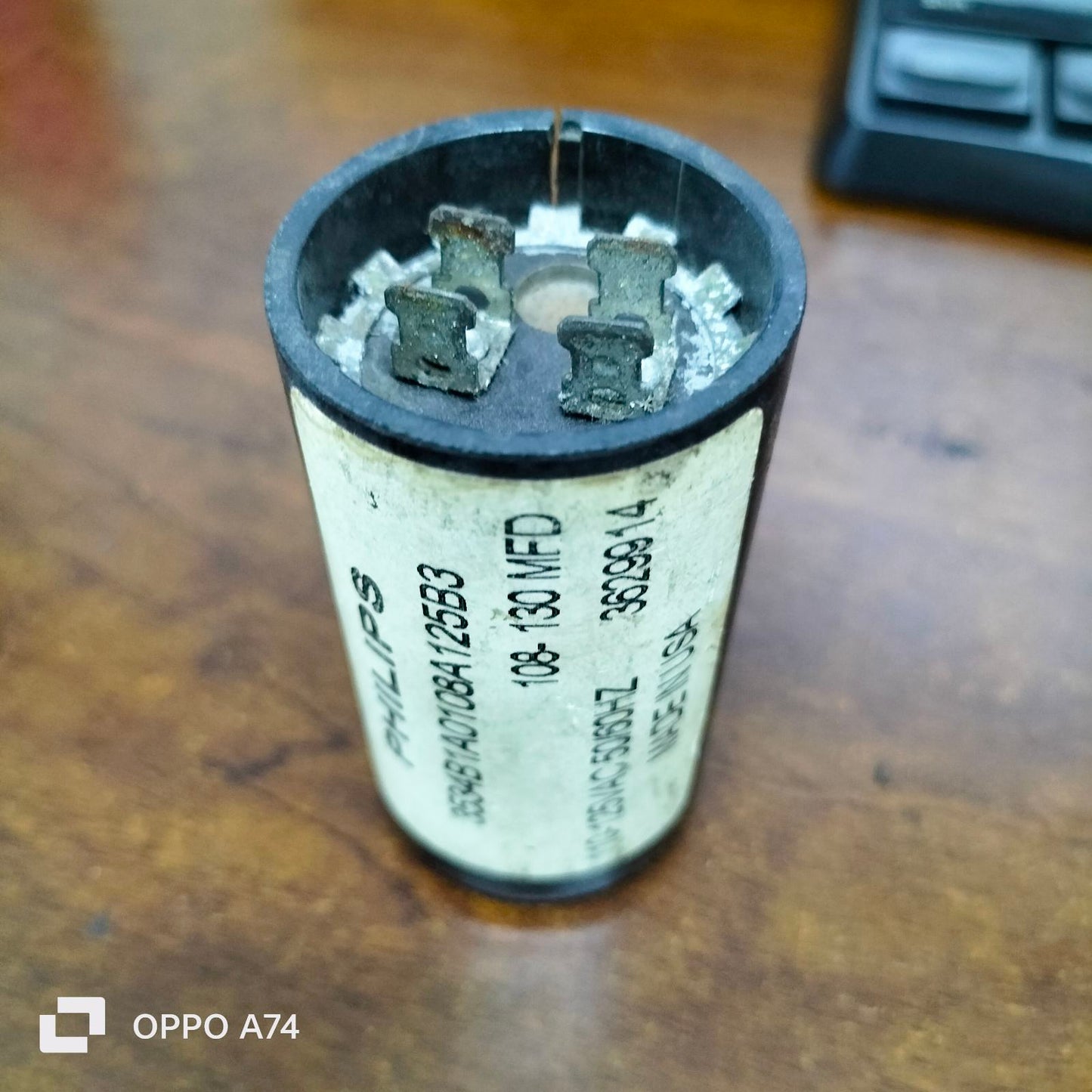 Philips Starting Capacitor 108-130 MFD electrical component with metal terminals on wooden surface
