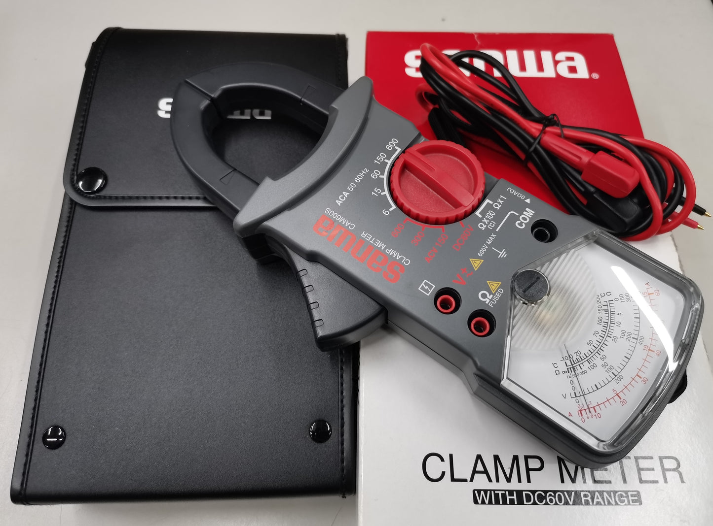 Sanwa Clamp Meter Max 600A CAM600S with red dial and test leads next to black carrying case