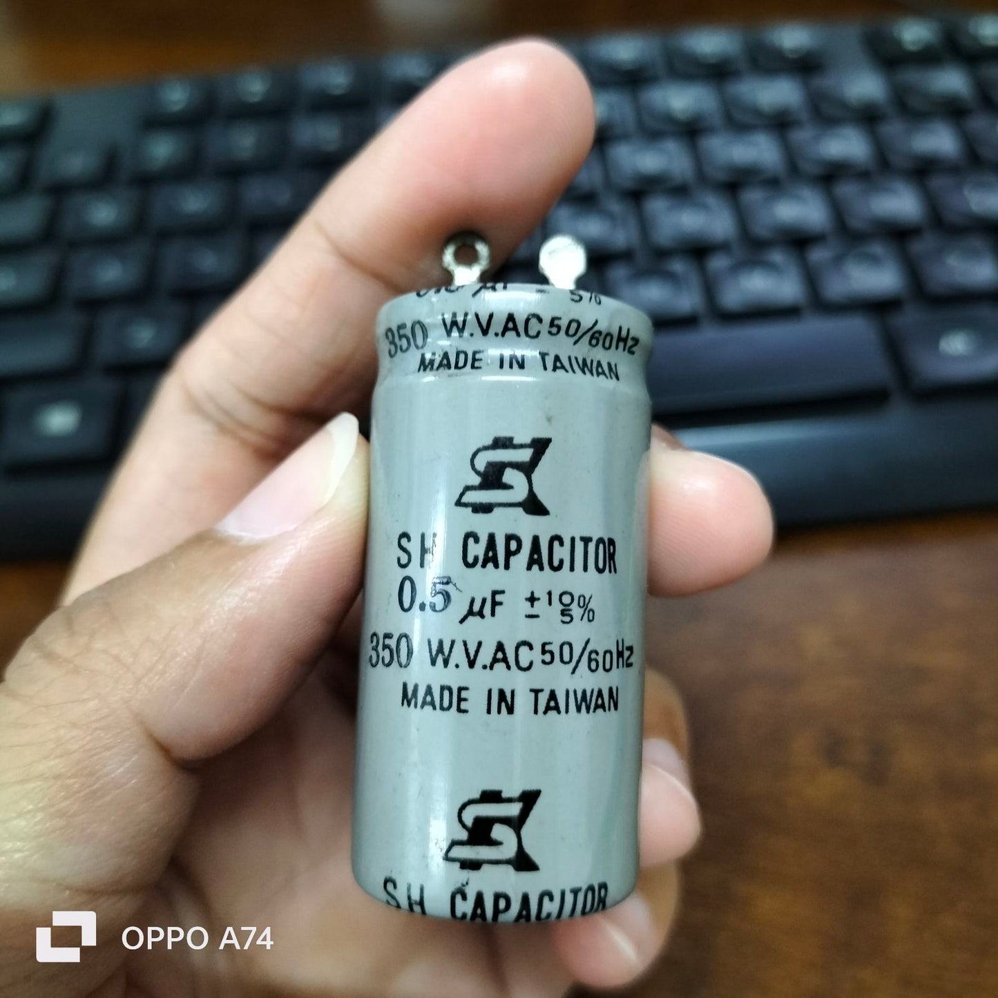 0.5MFD Motor Running Capacitor made in Taiwan held in hand with keyboard background