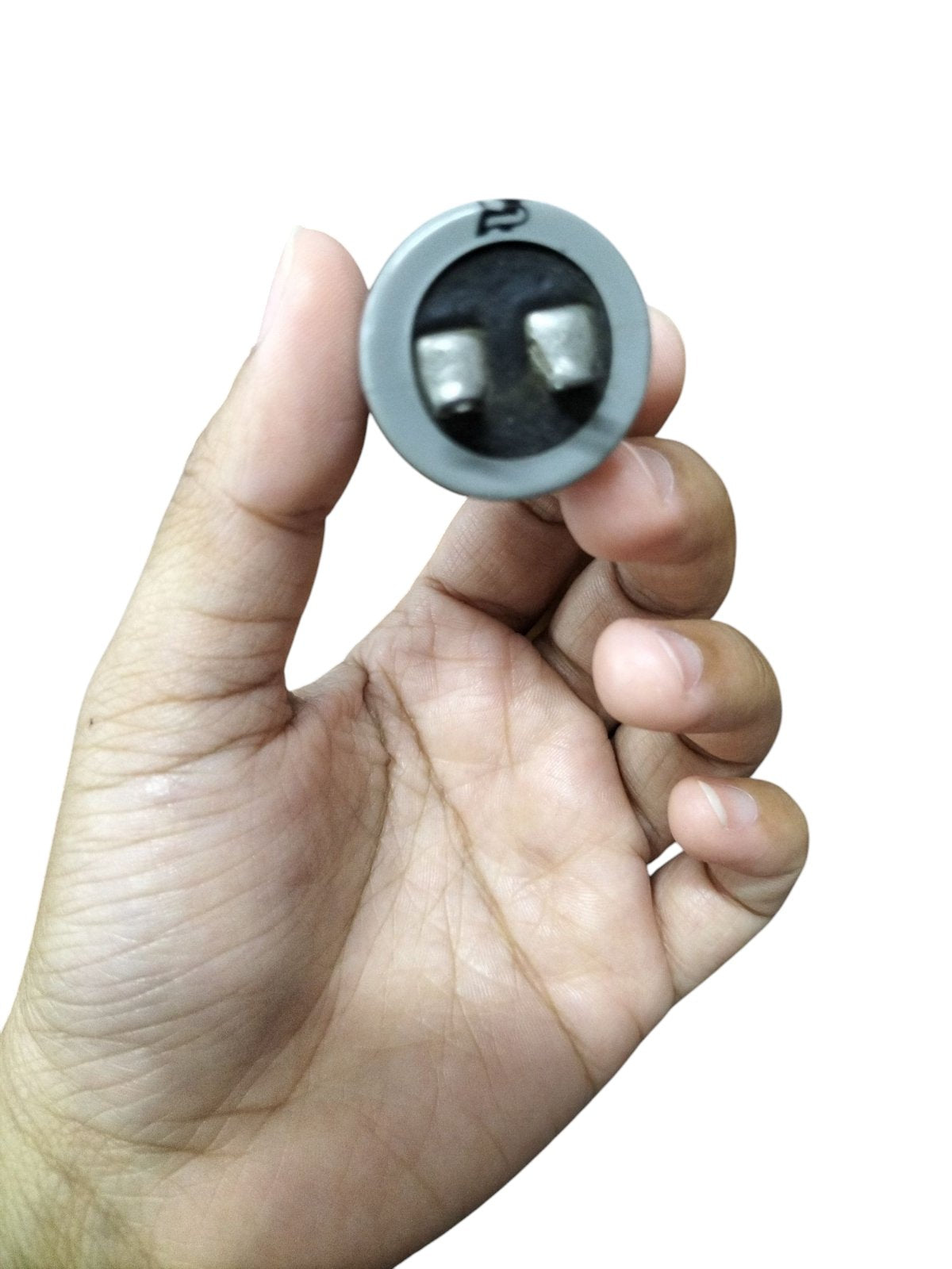 Hand holding SH Motor Running Capacitor 0.25UF 660V AC electrical component with two terminals