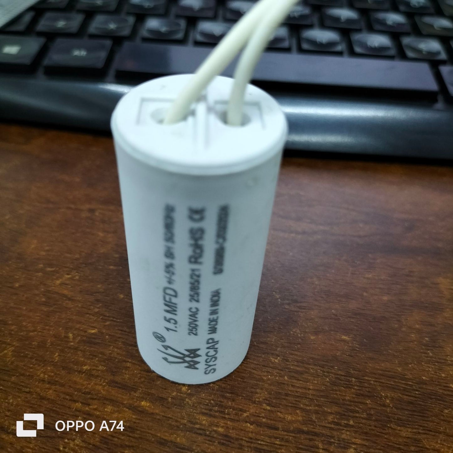 Syscap 1.5MFD 250V AC Motor Run Capacitor with white wires on a wooden surface