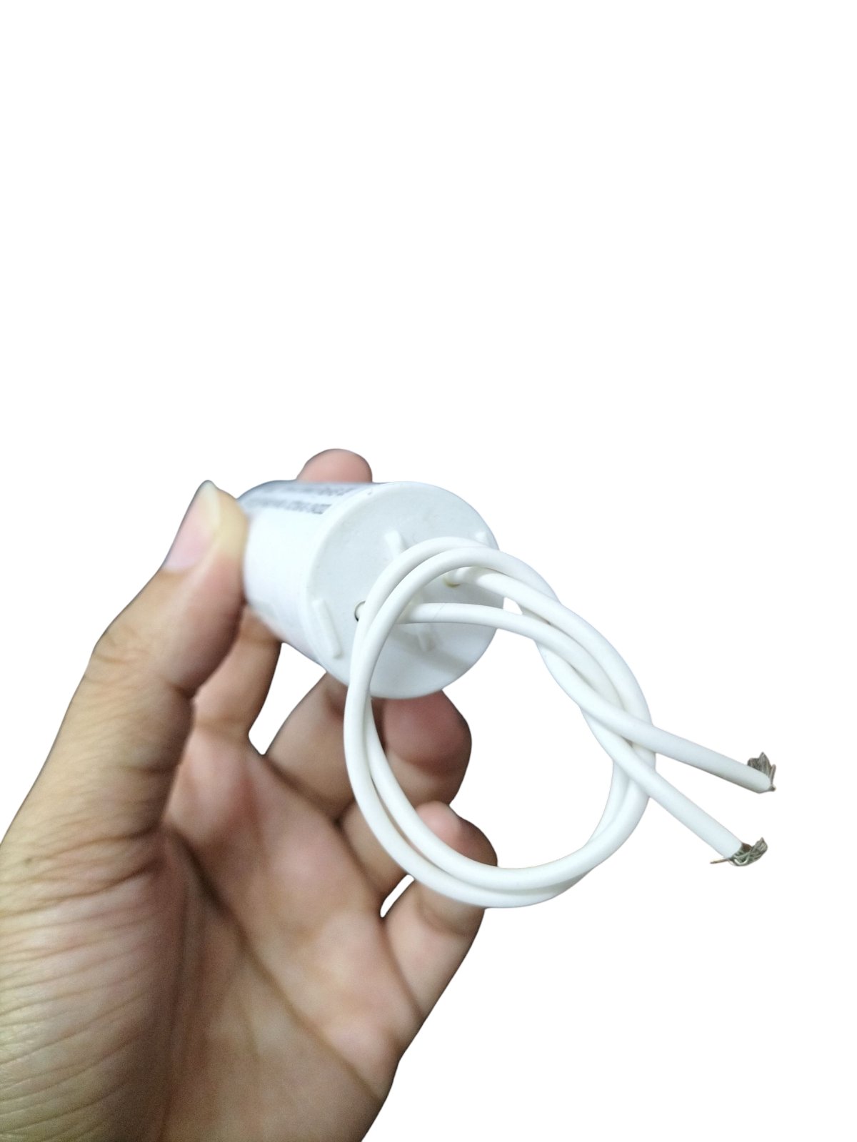 Syscap 2.5MFD motor running capacitor held in hand with white wires for electrical circuitry