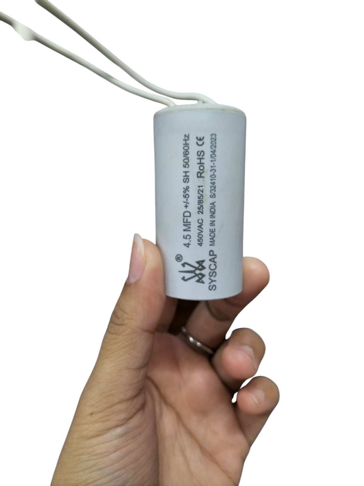 Syscap 4.5MFD motor capacitor white cylindrical electrical component held in hand