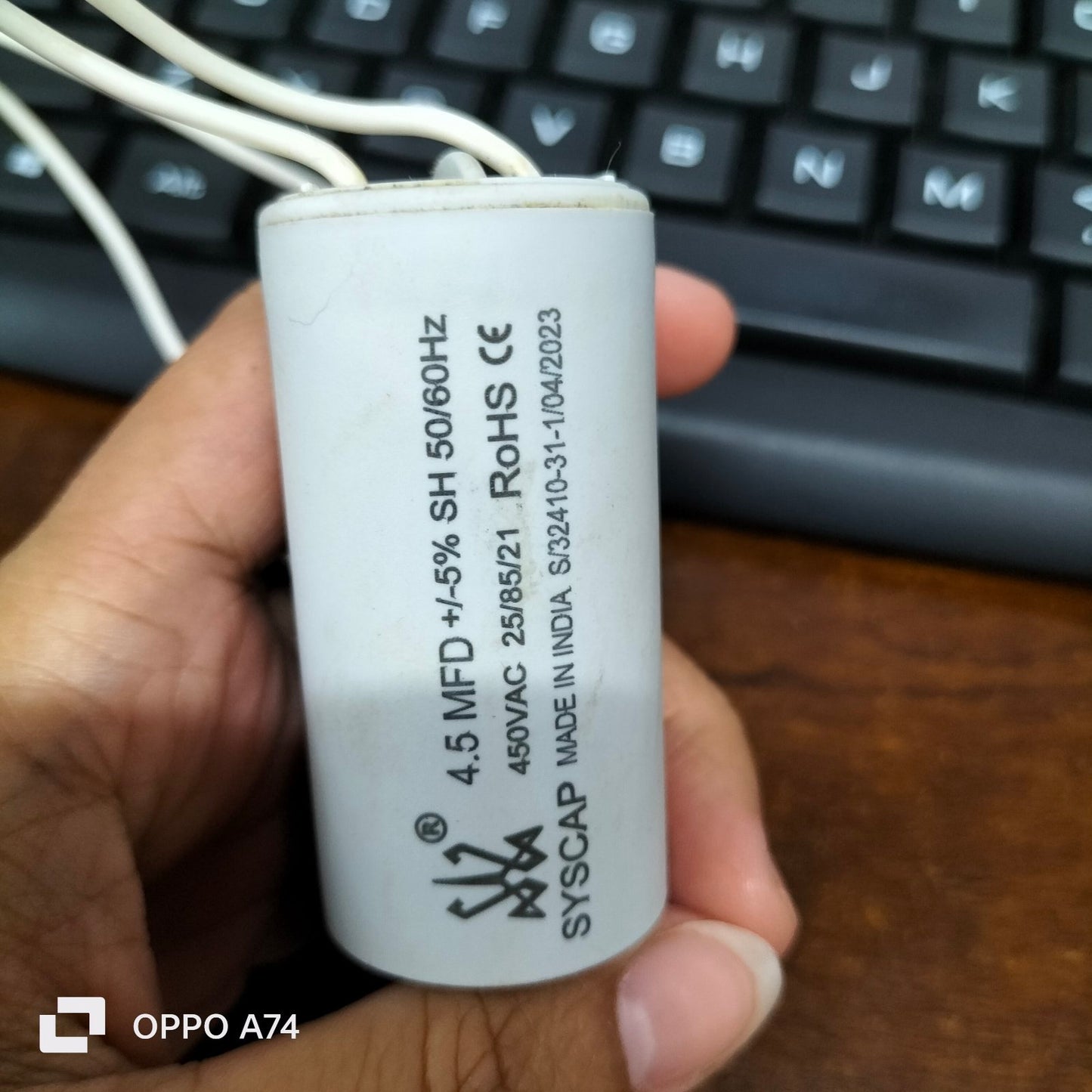 Syscap 4.5MFD motor capacitor white cylindrical electrical component with wires held in hand