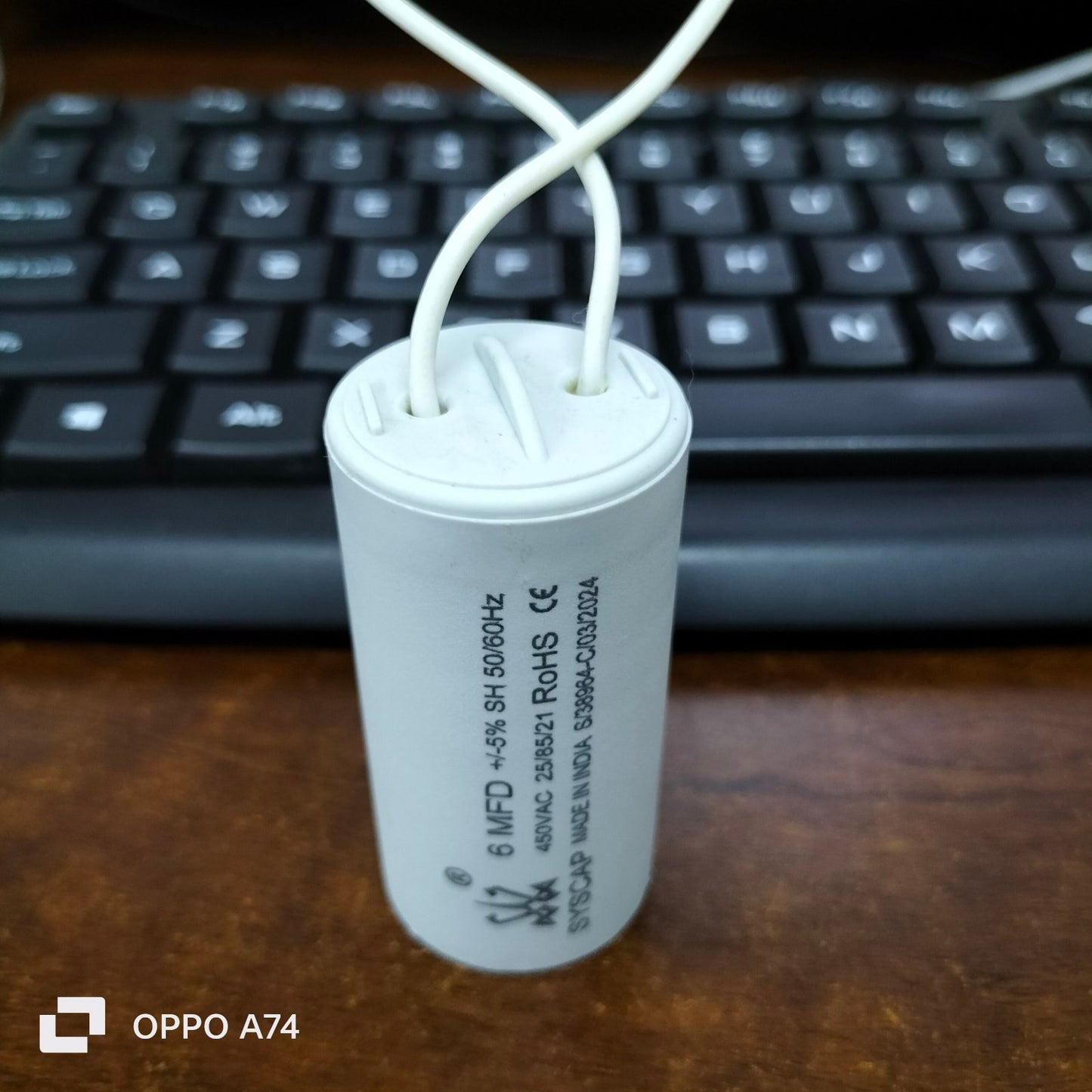 Syscap 6MFD Motor Running Capacitor white cylindrical electrical part with wires on wooden surface