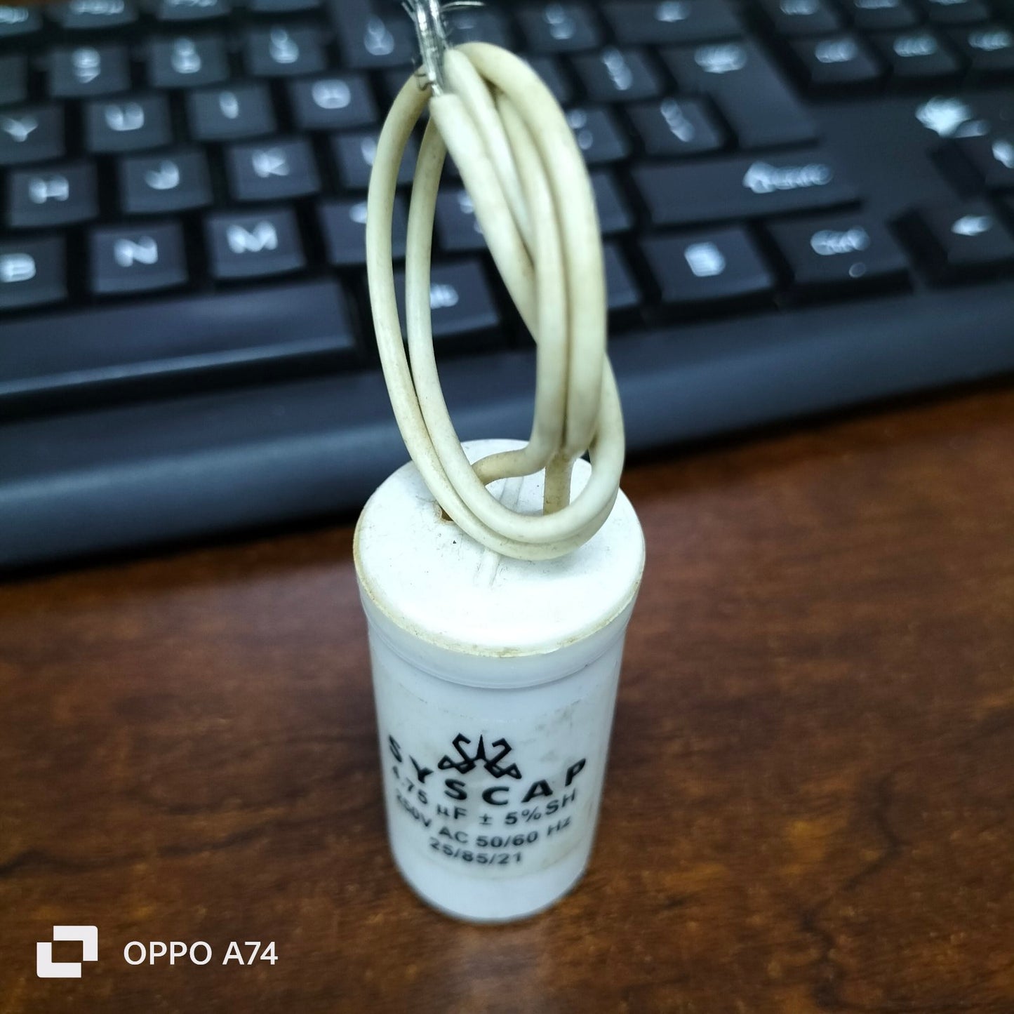 Syscap motor running capacitor 4.75MFD 250V with white cylindrical body and attached wire loop