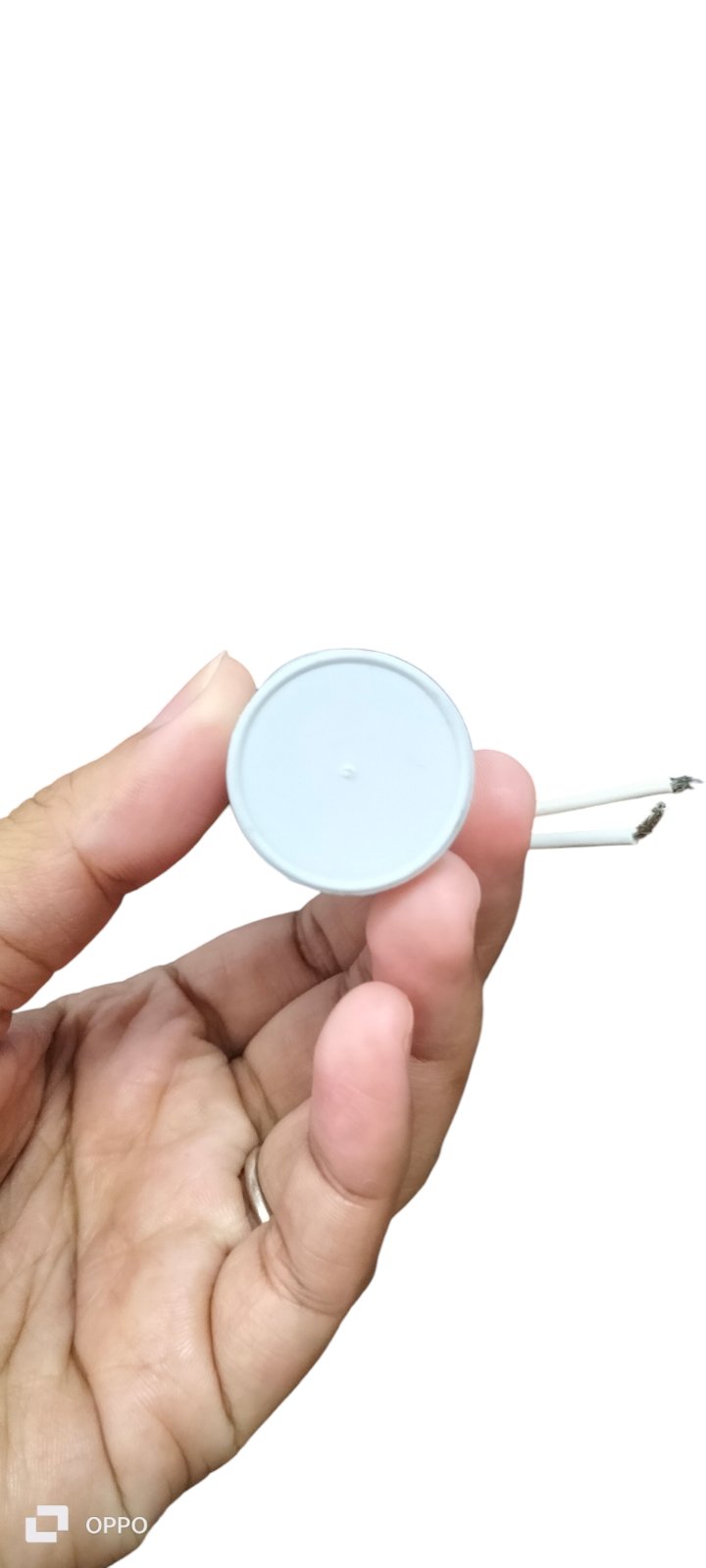 Hand holding Syscap Running Capacitor 4.75MFD 350 VAC electrical component with white casing and wires
