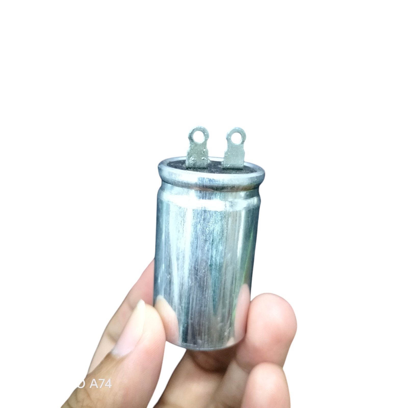SH brand 1.25MFD 250V AC capacitor held between fingers for electrical circuitry use