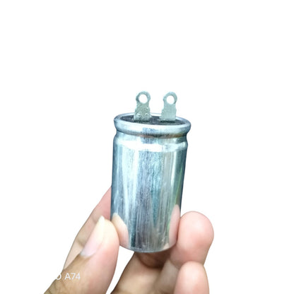 SH brand 1.25MFD 250V AC capacitor held between fingers for electrical circuitry use