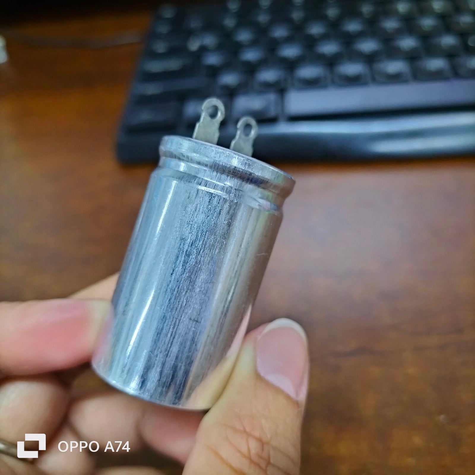 1.7UF motor running capacitor electrical circuitry part from Japan held in hand against keyboard background