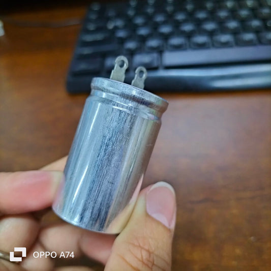 1.7UF motor running capacitor electrical circuitry part from Japan held in hand against keyboard background