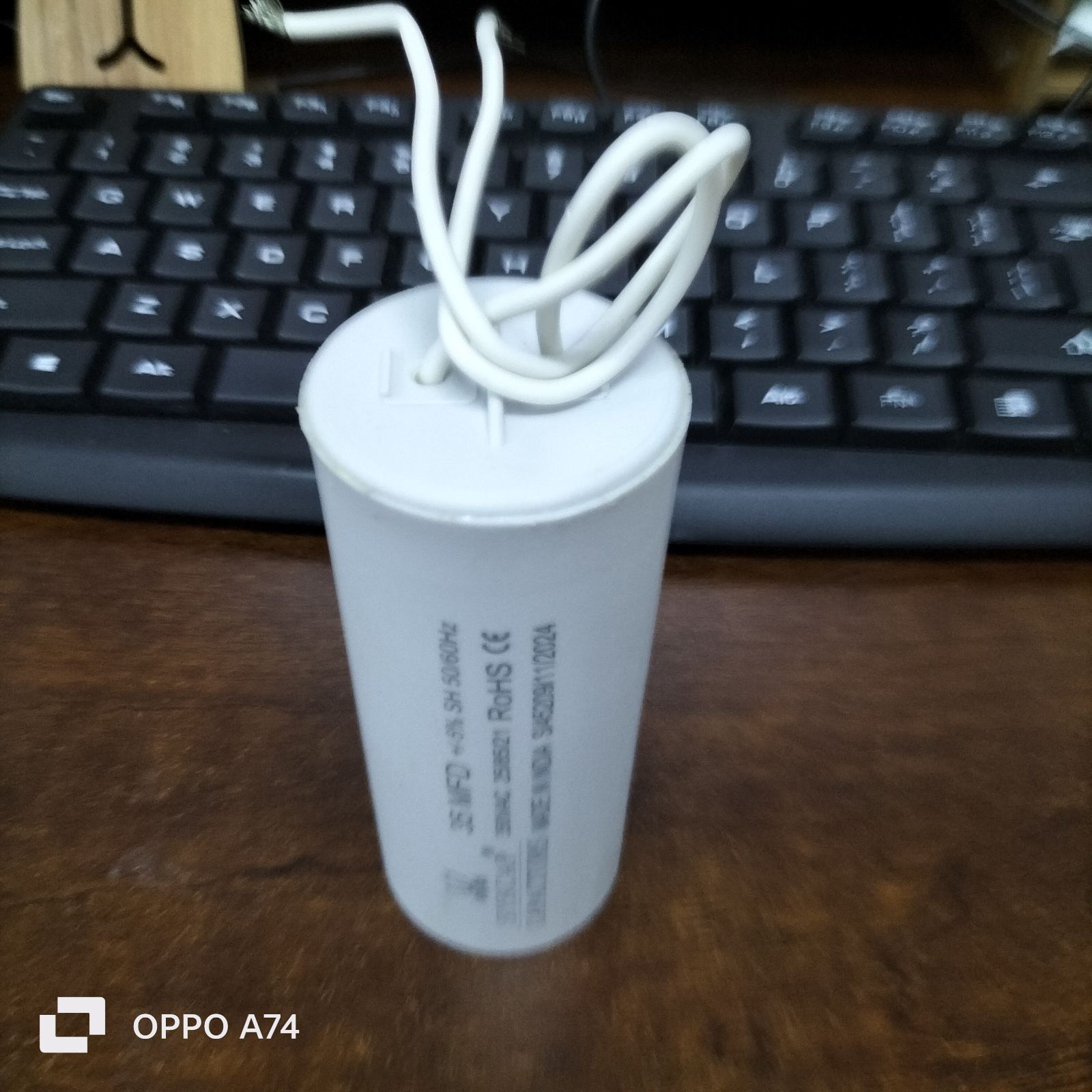 Syscap 35MFD 350 VAC Running Capacitor cylindrical electrical part with white wires on wooden desk