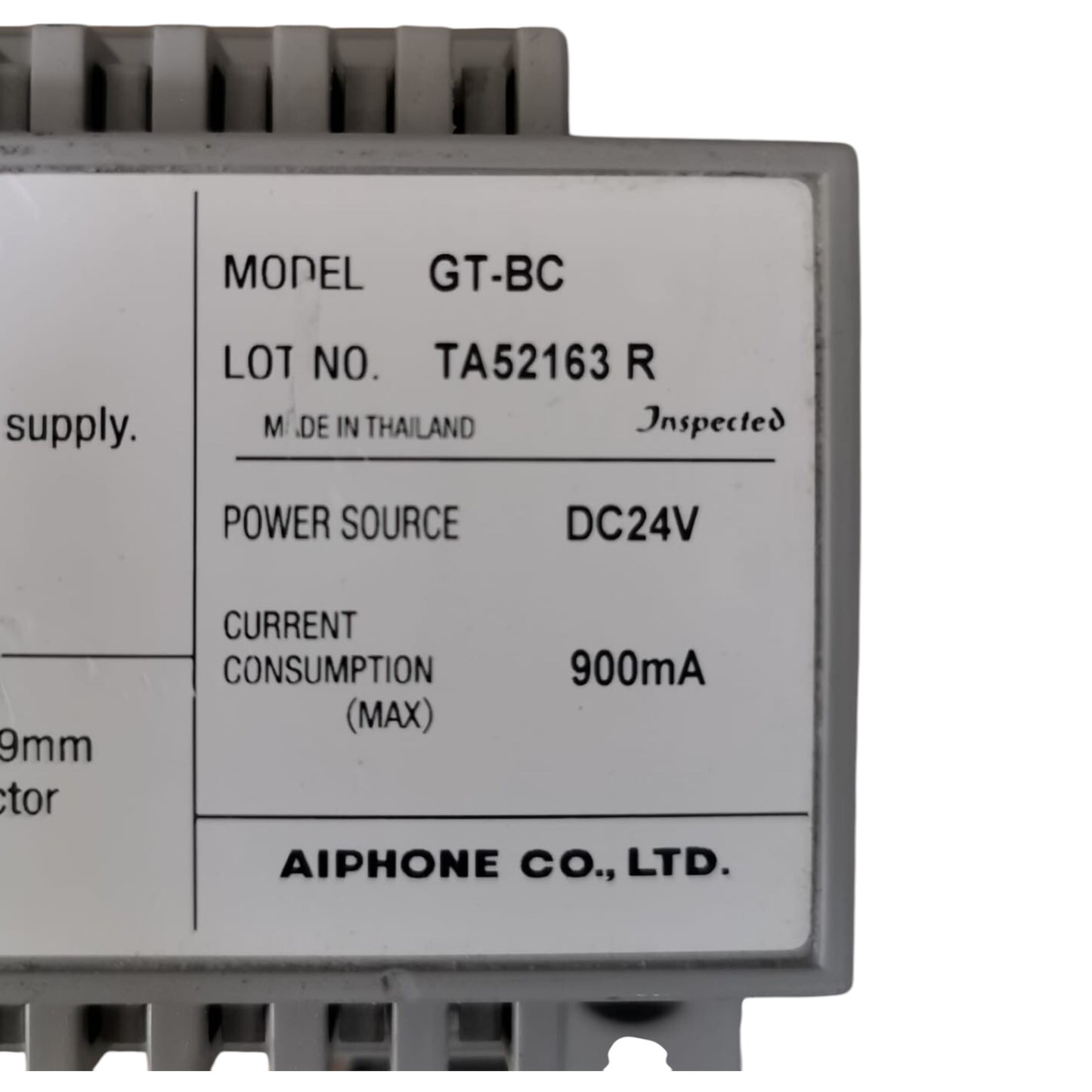 A close-up of a gray electronic module with a white label showing specifications including model GT-BC, manufacturer AIPHONE CO., LTD.