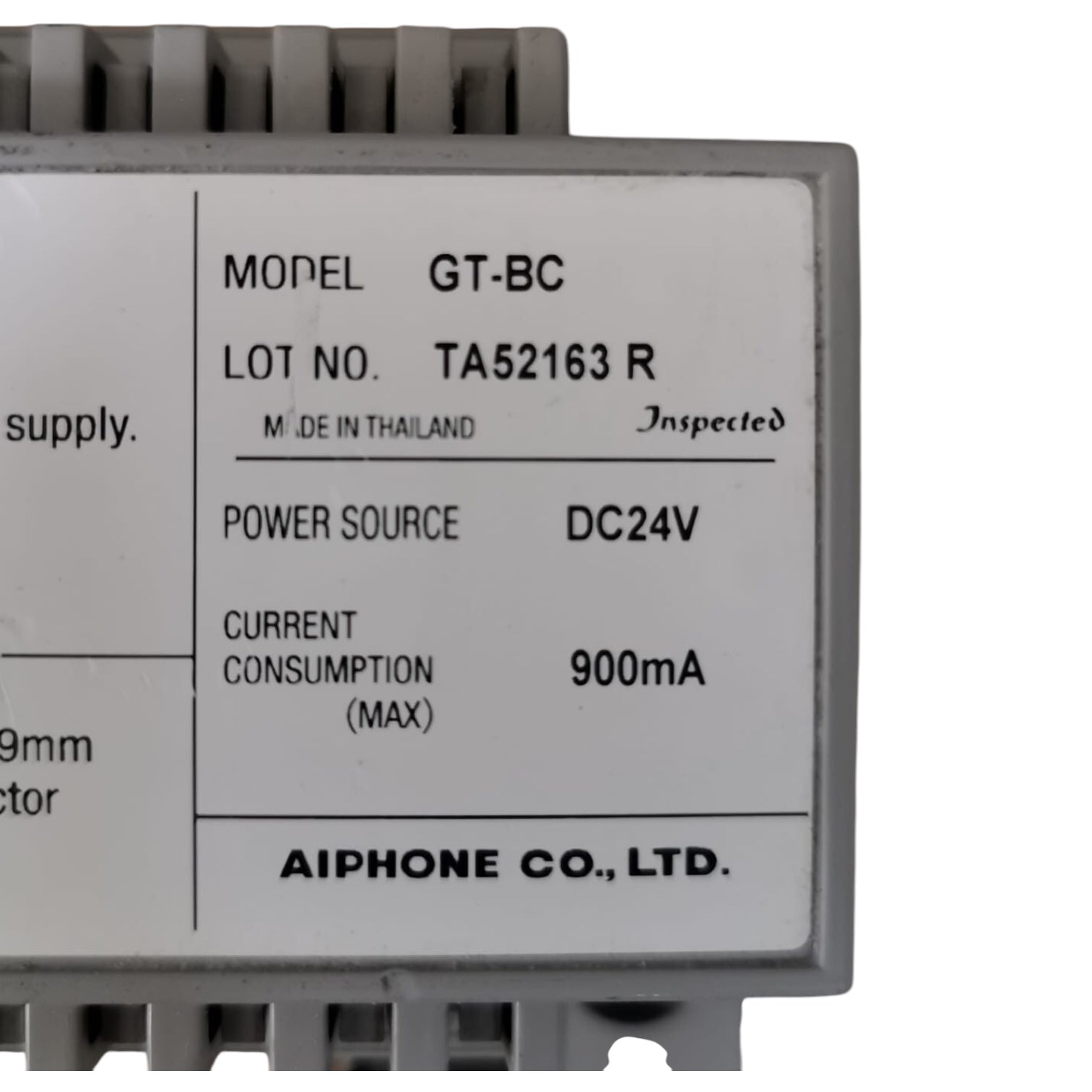 A close-up of a gray electronic module with a white label showing specifications including model GT-BC, manufacturer AIPHONE CO., LTD.