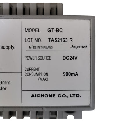 A close-up of a gray electronic module with a white label showing specifications including model GT-BC, manufacturer AIPHONE CO., LTD.