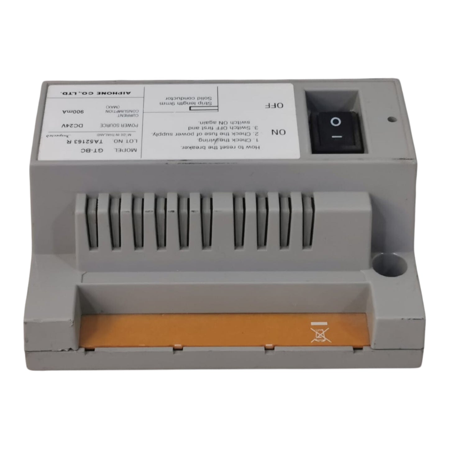 A gray industrial electronic module with a front switch, ventilation slots, and a gold contact terminal strip, photographed on a white background.
