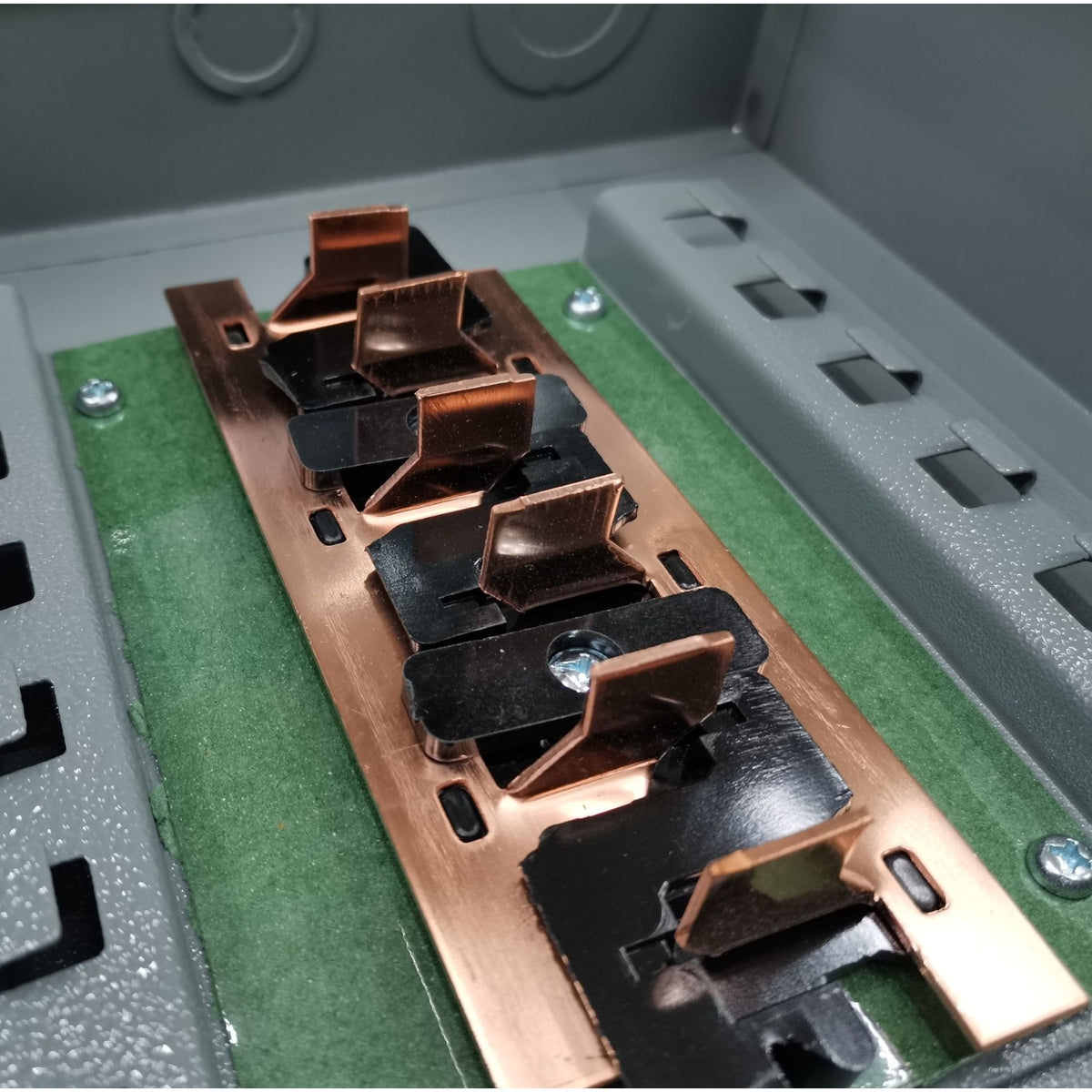 Close-up of a metallic component with copper and black finishes on a green and gray background.