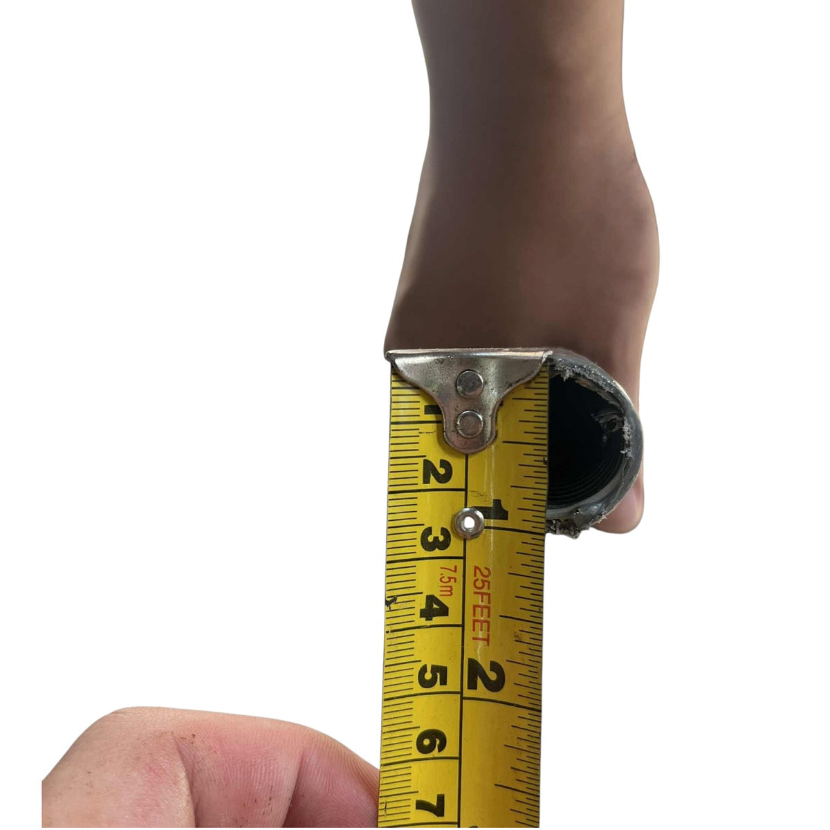 A close-up of a person's foot and hand holding a yellow tape measure against a white background to show the width of a circular opening.