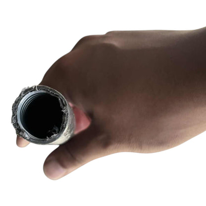 A close-up of a hand holding a cylindrical metal pipe fitting or tube end against a plain white background.