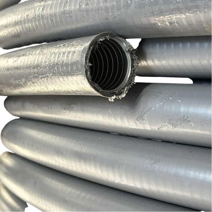 Close-up of several gray corrugated plastic pipes stacked together, with one pipe cut open to show the ribbed inner wall.