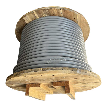 A large spool of gray corrugated industrial pipe or conduit, wound tightly on a wooden spool with wooden support blocks visible at the base, isolated on a white background.