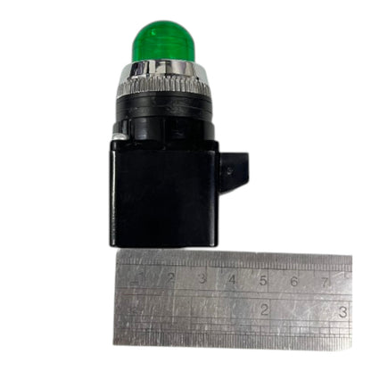 A small black electrical indicator light with a green dome bulb and a silver ribbed metal collar, shown above a metal ruler for scale on a white background.