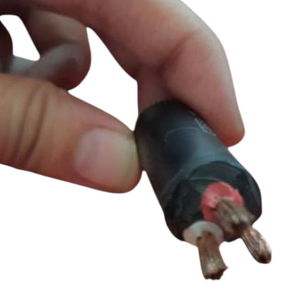A close-up of a hand holding a small black electrical cable with two exposed copper wires and a red insulating detail, isolated on a white background.