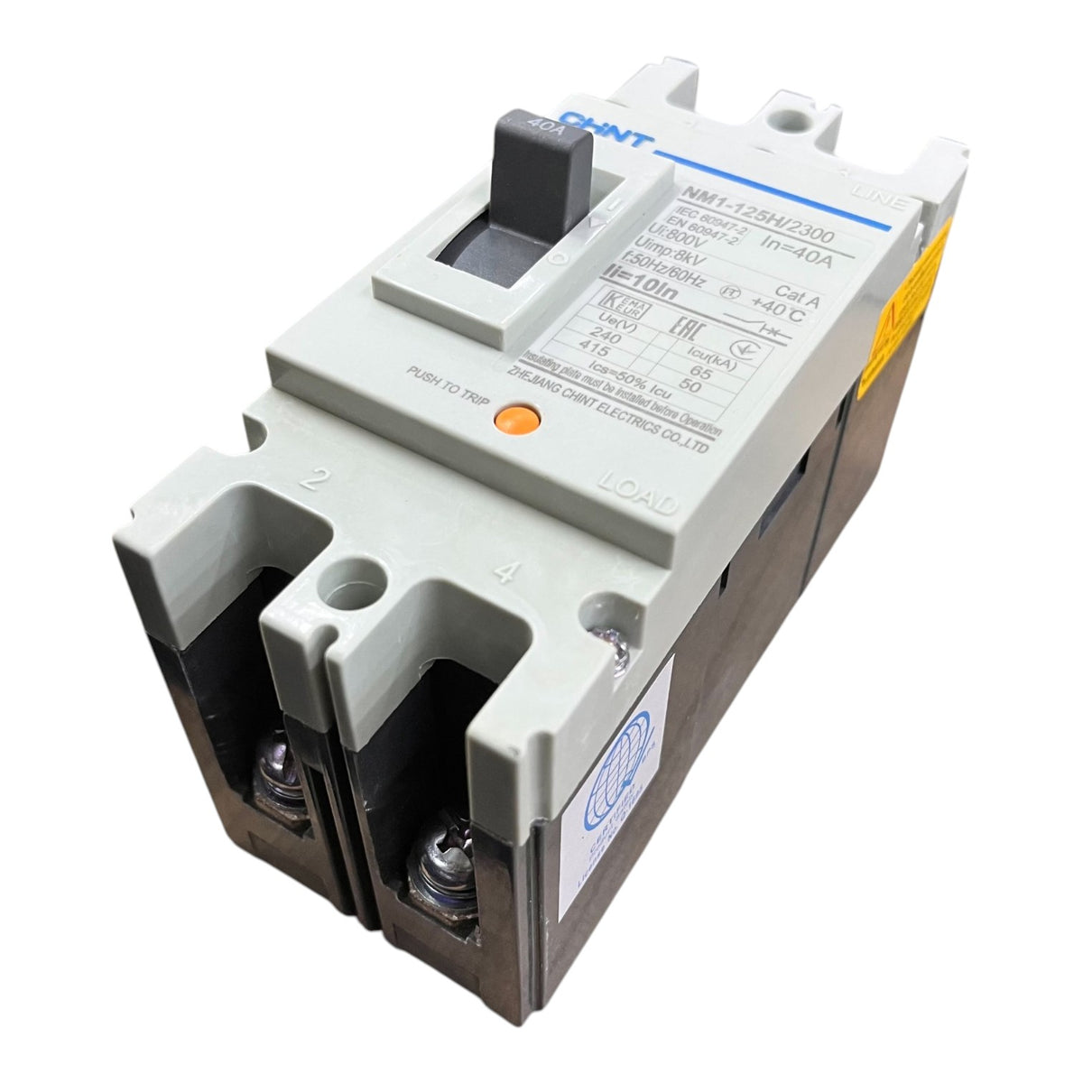 A compact molded circuit breaker with a gray top housing, black front terminal covers, and printed technical specifications on the side, photographed on a plain white background.