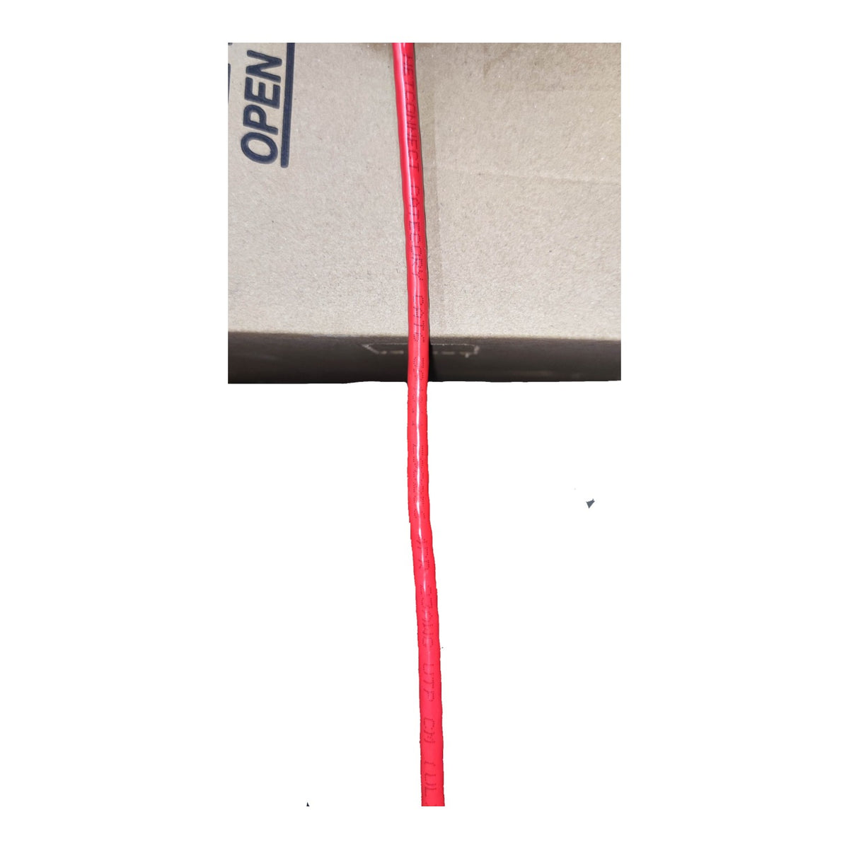 A single bright red cord or cable running vertically down the center, photographed against a plain white background with a cardboard box edge visible at the top.